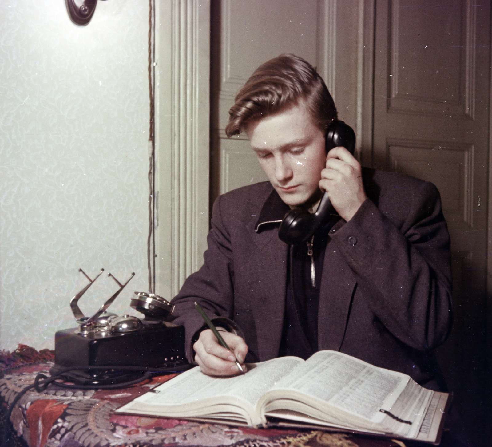 Hungary, Budapest XIII., a felvétel a Bulcsú utca 21/a számú ház egyik lakásában készült., 1955, Ungváry Rudolf, Budapest, photo aspect ratio: square, writing, telephone, teenager, boy, hairdo, jacket, phone book, colorful, Best of, Fortepan #254822