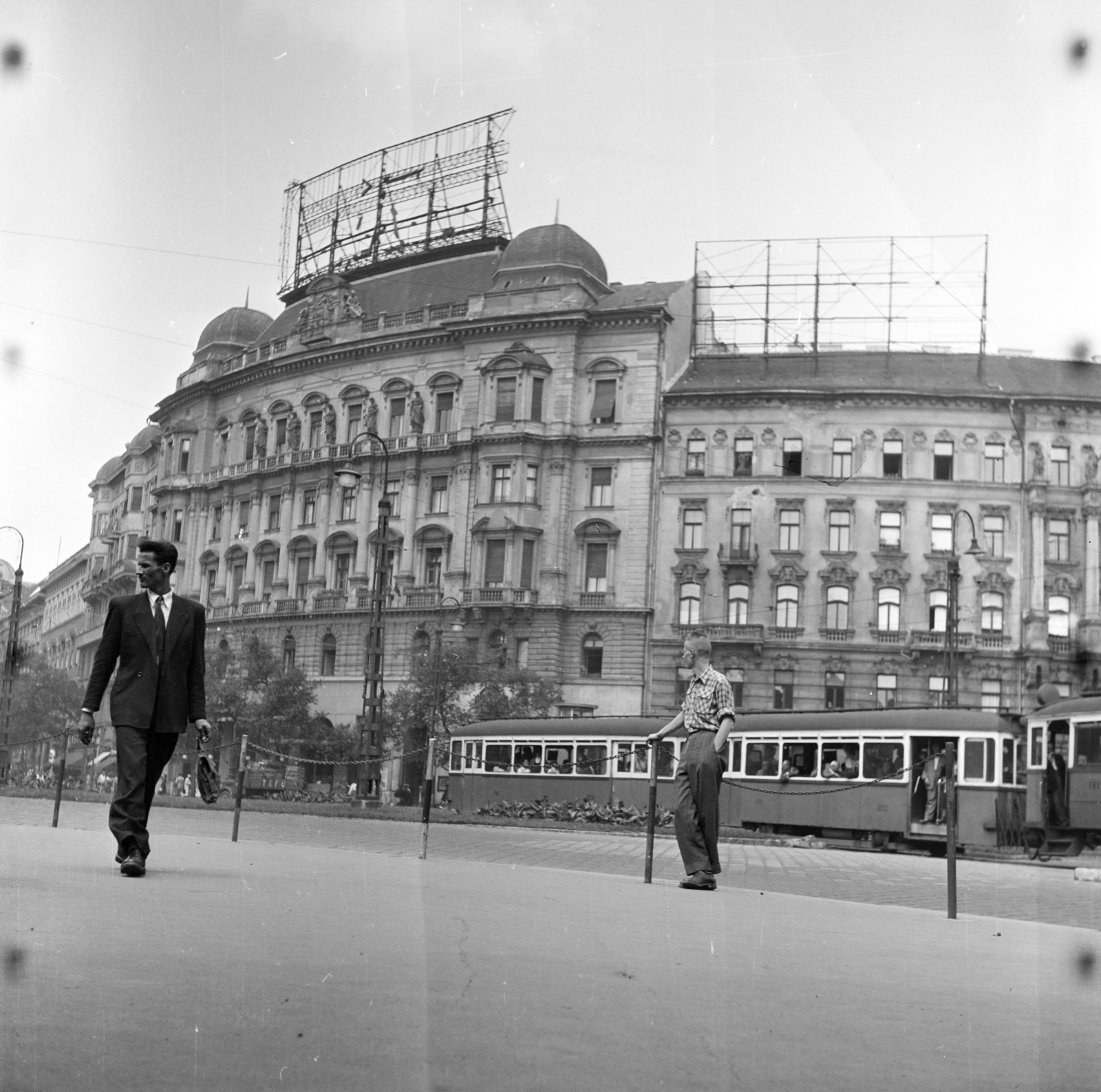 Magyarország, Budapest XIII., Nyugati (Marx) tér, szemben az 5-ös és 4-es számú ház., 1957, Ungváry Rudolf, Best of, Budapest, villamos, hajviselet, képarány: négyzetes, korlát, zsebredugott kéz, kockás ing, híres ember, épületszobor, aktatáska, Fortepan #254866
