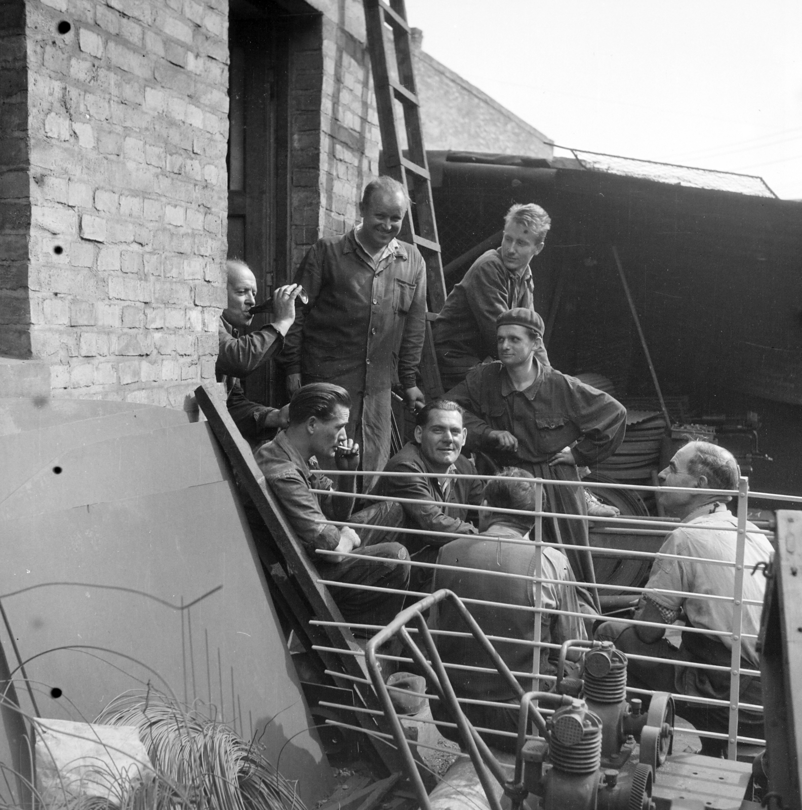 Magyarország, Budapest XIII., Kassák Lajos utca (Fóti út) 13., Lakatos- és Fémáru Kisipari Termelő Szövetkezet. A lakatosműhely szakmunkásai ebédszünetben a műhely bejáratánál., 1958, Ungváry Rudolf, Budapest, képarány: négyzetes, pihenés, ivás, dohányzás, Fortepan #254915