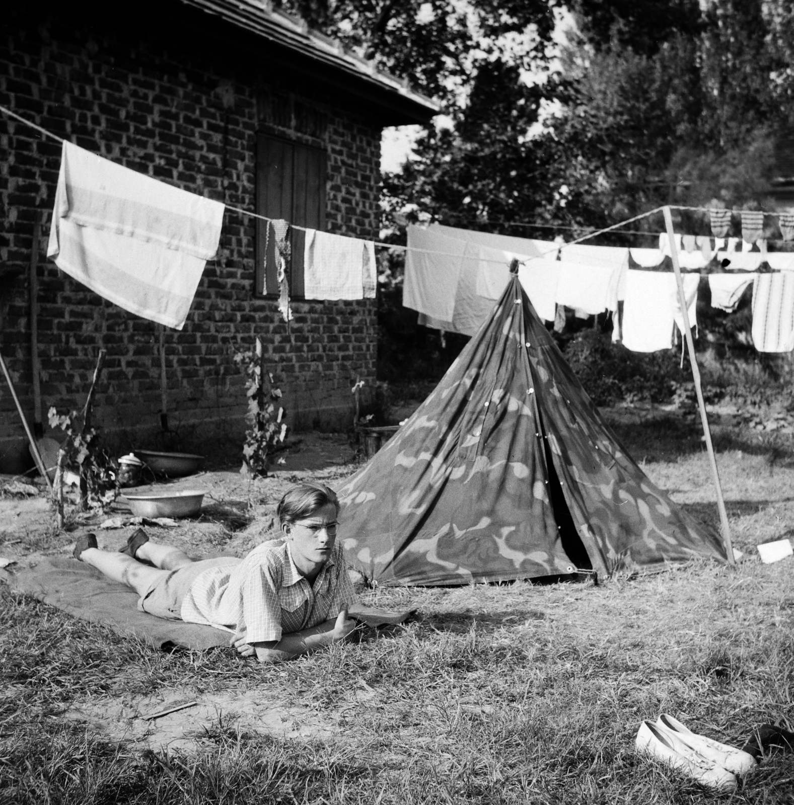 Hungary, Balatonszemes, Berzsenyi Dániel utca 15., 1955, Ungváry Rudolf, photo aspect ratio: square, relaxation, tent, plaid, yard, camouflage pattern, lying on stomach, hanging clothes, Fortepan #254966