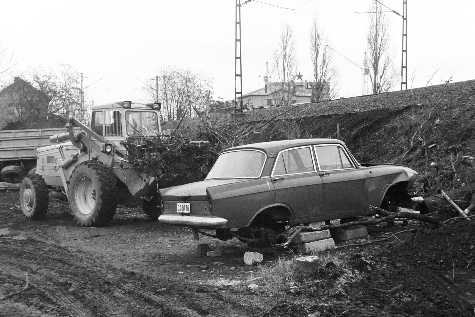 Hungary, Budapest XI., Hamzsabégi út, vasúti töltés a Kelenföldi buszgarázssal szemben. A vörös csillagos épület a Budapesti Tejipari Vállalat (BTV) Kelenföldi Tejüzem (Bartók Béla út 105-113.), mögötte épül a Tétényi út 1-3. számú panelház., 1983, Bojár Sándor, Budapest, Red Star, tractor, Moskvitch-brand, wreck, Volvo-brand, Volvo BM, Fortepan #255316