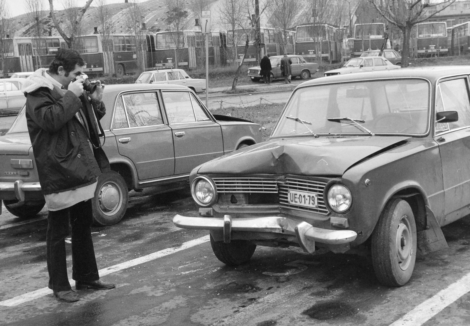 Magyarország, Budapest XI., Hamzsabégi út 60., az Ál­lami Biztosító Budapesti Gépjárműkárrendezési Központ kárfelvevő helye. Háttérben a Kelenföldi buszgarázs., 1984, Bojár Sándor, Budapest, rendszám, járműroncs, fényképezőgép, fotózás, Fortepan #255374