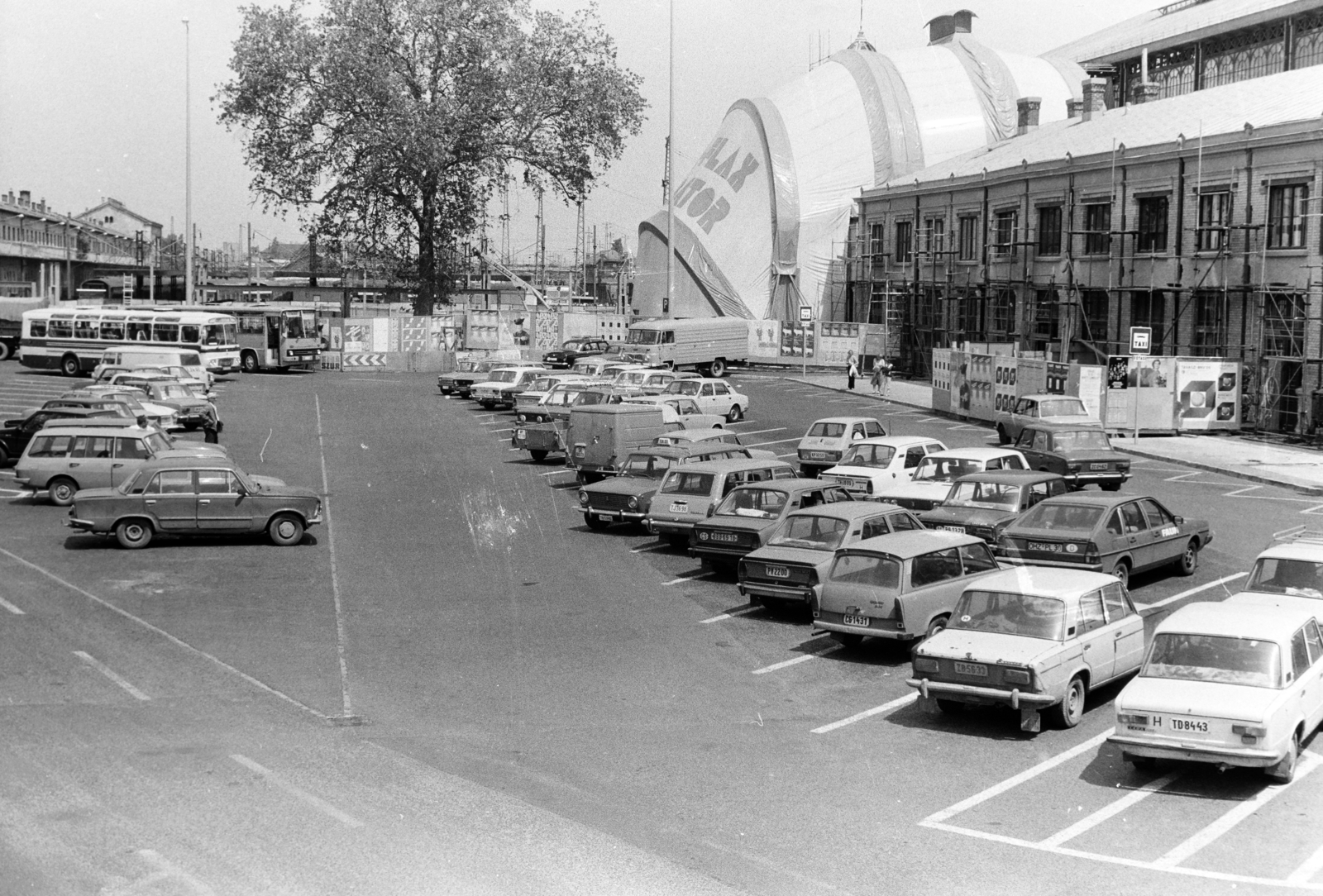 Magyarország, Budapest VI., parkoló a Nyugati pályaudvar érkezési oldalánál. Szemben a kormányváró felújításakor használt védősátor látható., 1984, Bojár Sándor, Budapest, automobil, sátor, parkoló, Fortepan #255442