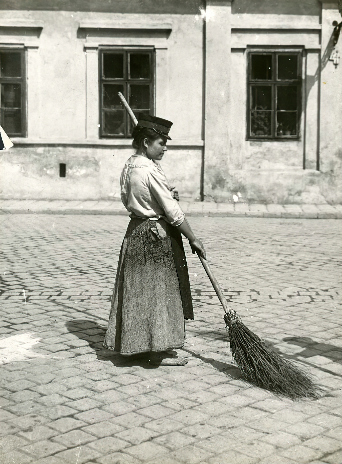 Hungary, Budapest VIII., a Vásár utca (Rákóczi tér) és a Víg utca kereszteződése. A felvétel az I. világháború kitörése utáni mozgosítás idején, 1914. augusztus 15-én készült., 1914, Országos Széchényi Könyvtár, sweeper, woman, Budapest, broom, cobblestones, Fortepan #256219
