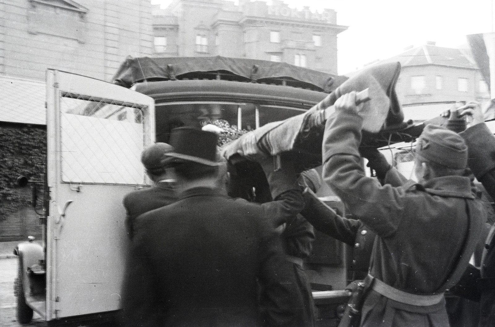 Magyarország, Budapest I.,Budapest XII., Déli pályaudvar, mentőautóba emelik át a vöröskeresztes kórházvonatból a hordágyat. Középen háttérben az Alkotás utca 13-as számú ház látható a Greguss utca sarkán., 1942, Reményi József, Budapest, fej fölé emelés, Fortepan #257591