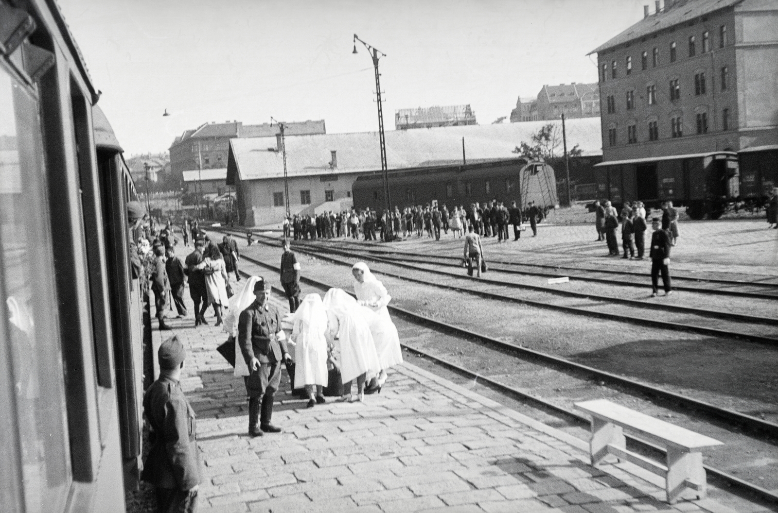 Magyarország, Budapest I., Déli pályaudvar, a 154-es számú vöröskeresztes kórházvonat és személyzete indulásra várva. Háttérben a raktárépületektől távolabb a Győri út és a Márvámy utca sarokán álló ház látható., 1942, Reményi József, Budapest, pad, Fortepan #257760