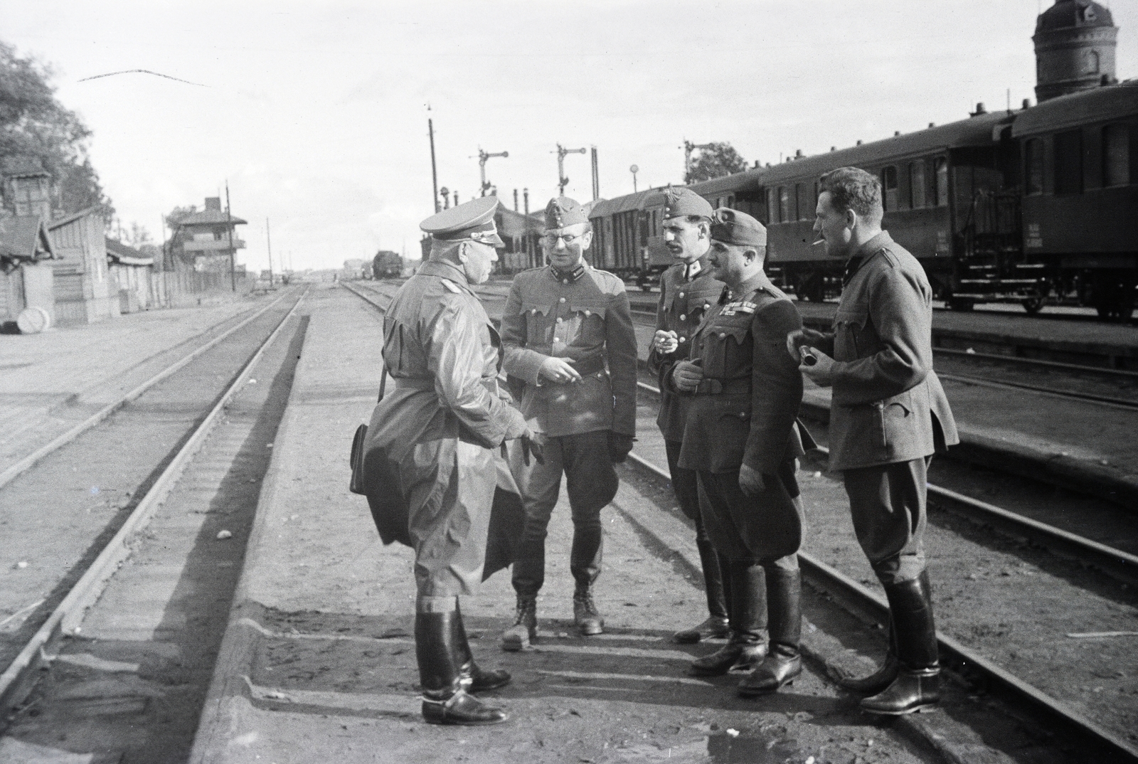 Fehéroroszország, Homel, vasútálllomás, a háttérben jobbra a vöröskeresztes kórházvonat látható., 1942, Reményi József, katona, bakancs, csizma, orkánkabát, beszélgetés, Fortepan #258233