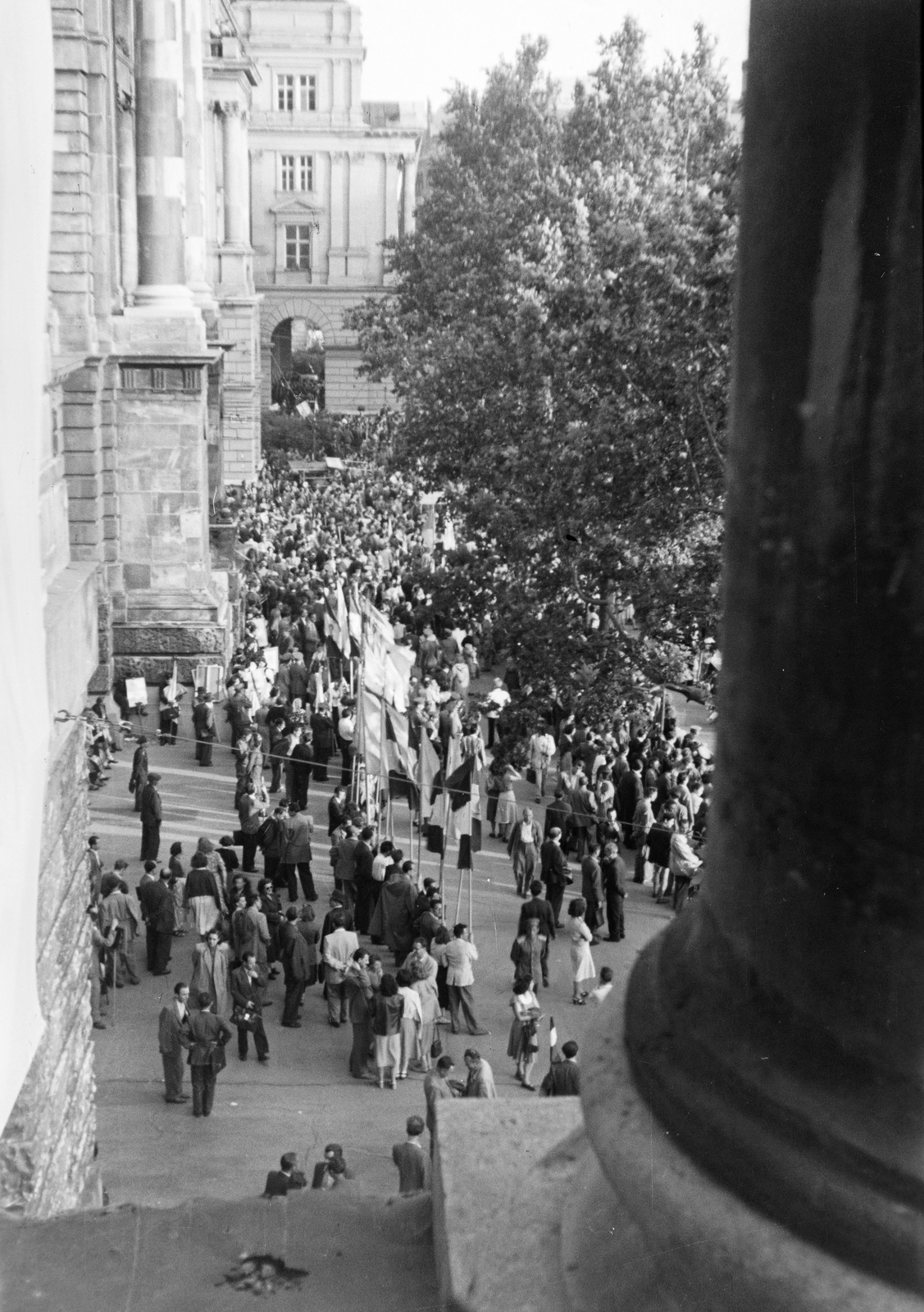 Magyarország, Budapest V., Kossuth Lajos tér, kilátás az Igazságügyi Palota (ekkor a Magyar és Nemzetközi Munkásmozgalom Történeti Múzeuma) épületének teraszáról a Földművelésügyi Minisztérium felé. Békenagygyűlés résztvevői a Békevilágtanács Budapesten megrendezett ülésének alkalmából. A felvétel 1953. június 19. -én készült., 1954, Reményi József, tömeg, zászló, bámészkodás, felülnézet, Budapest, Fortepan #258443