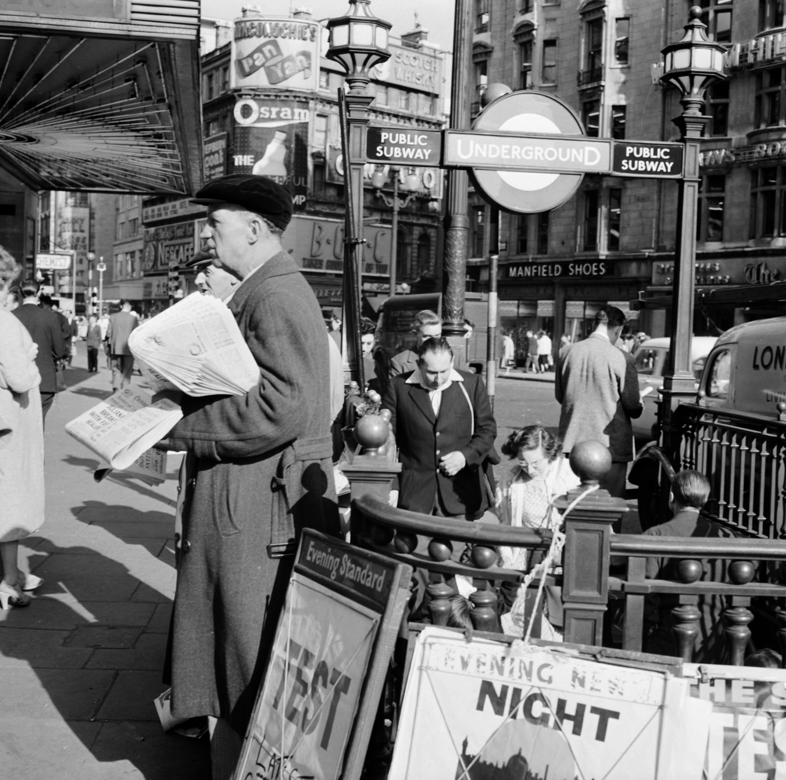 United Kingdom, London, a felvétel a Shaftesbury Avenue és a Coventry Street sarkán, a London Pavilion előtt készült, a Piccadilly Circus metróállomásnál., 1956, UWM Libraries, newsstand, English sign, ad, photo aspect ratio: square, Fortepan #258857