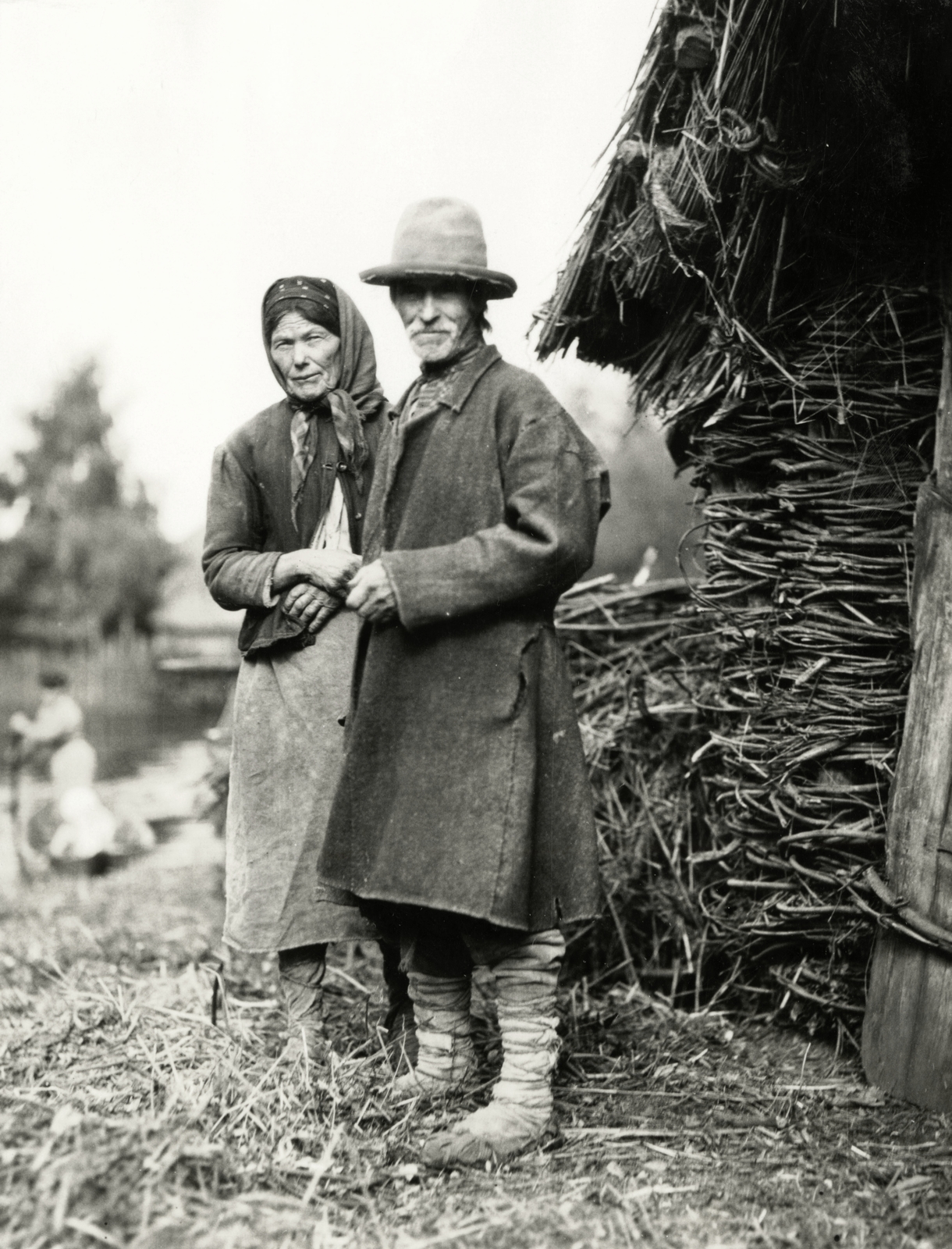 Belarus, a halász és felesége egy magtár előtt állnak, házi szőttes ruhát viselnek. Mindkettőjük lába nyírfa kéreggel van körbetekerve., 1934, UWM Libraries, Fortepan #258986