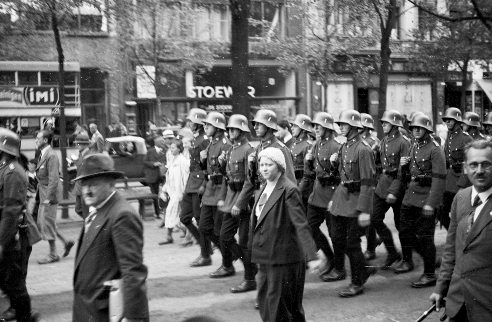 Németország, Berlin, Unter den Linden, háttérben középen az ekkor 64. számú ház (később 52). Katonák felvonulása örségváltáshoz., 1934, UWM Libraries, Clarence Woodrow Sorensen, felvonulás, német katona, rohamsisak, karszalag, Fortepan #259333