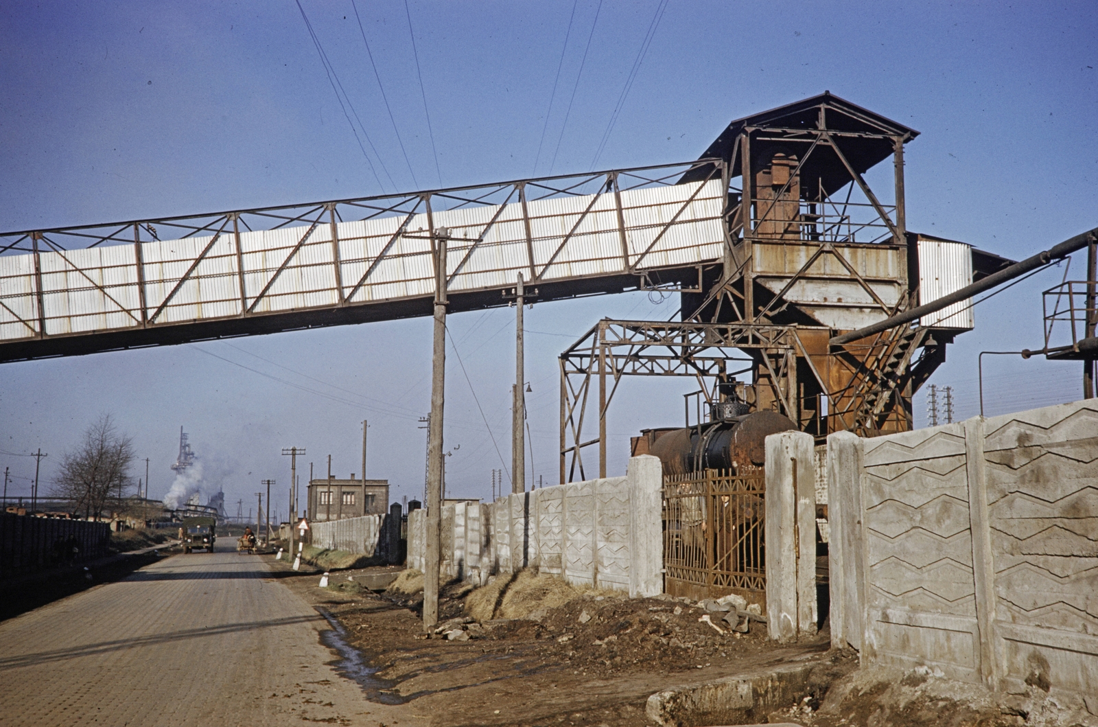 Hungary, Dorog, Esztergomi út, balra a Dorogi Szénfeldolgozó Vegyipari Vállalat (később a Kőbányai Gyógyszerárugyár Dorogi Gyáregysége), jobbra a kerítés mögött a vasútállomás területe., 1960, UWM Libraries, conveyor belt, industrial building, colorful, Fortepan #259490