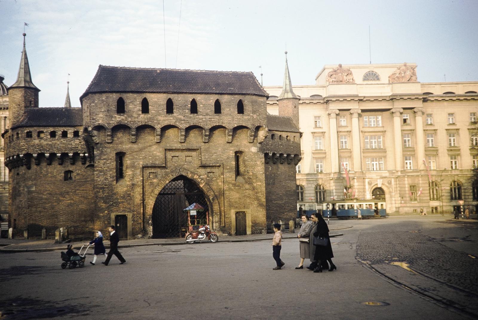 Lengyelország, Krakkó, ulica Basztowa, balra a barbakán, jobbra a háttérben a Lengyel Nemzeti Bank épülete, 1960, UWM Libraries, Harrison Forman, babakocsi, motorkerékpár, színes, villamos, várkapu, Fortepan #260237