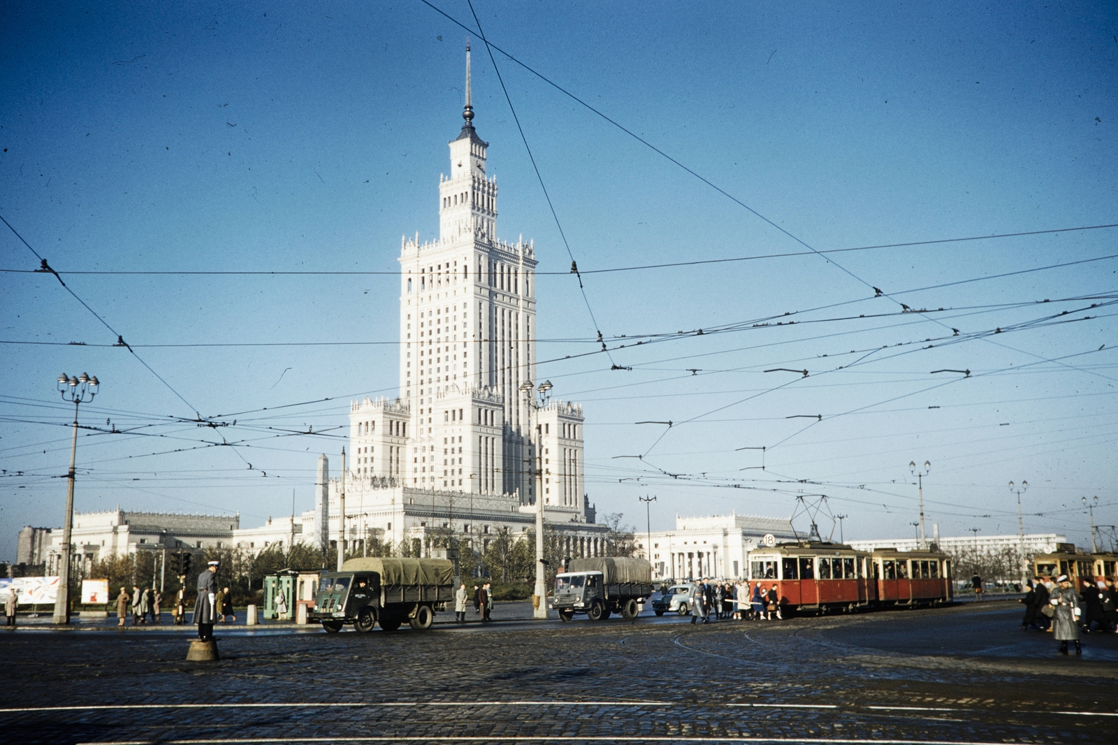 Lengyelország, Varsó, plac Defilad (Felvonulás tér), a Kultúra és Tudomány Palotája a mai Rondo Romana Dmowskiego (Aleje Jerozolimskie - ulica Marszalkowska kereszteződés) felől., 1960, UWM Libraries, Harrison Forman, színes, villamos, felsővezeték, magasház, rendőrdobogó, Fortepan #260293