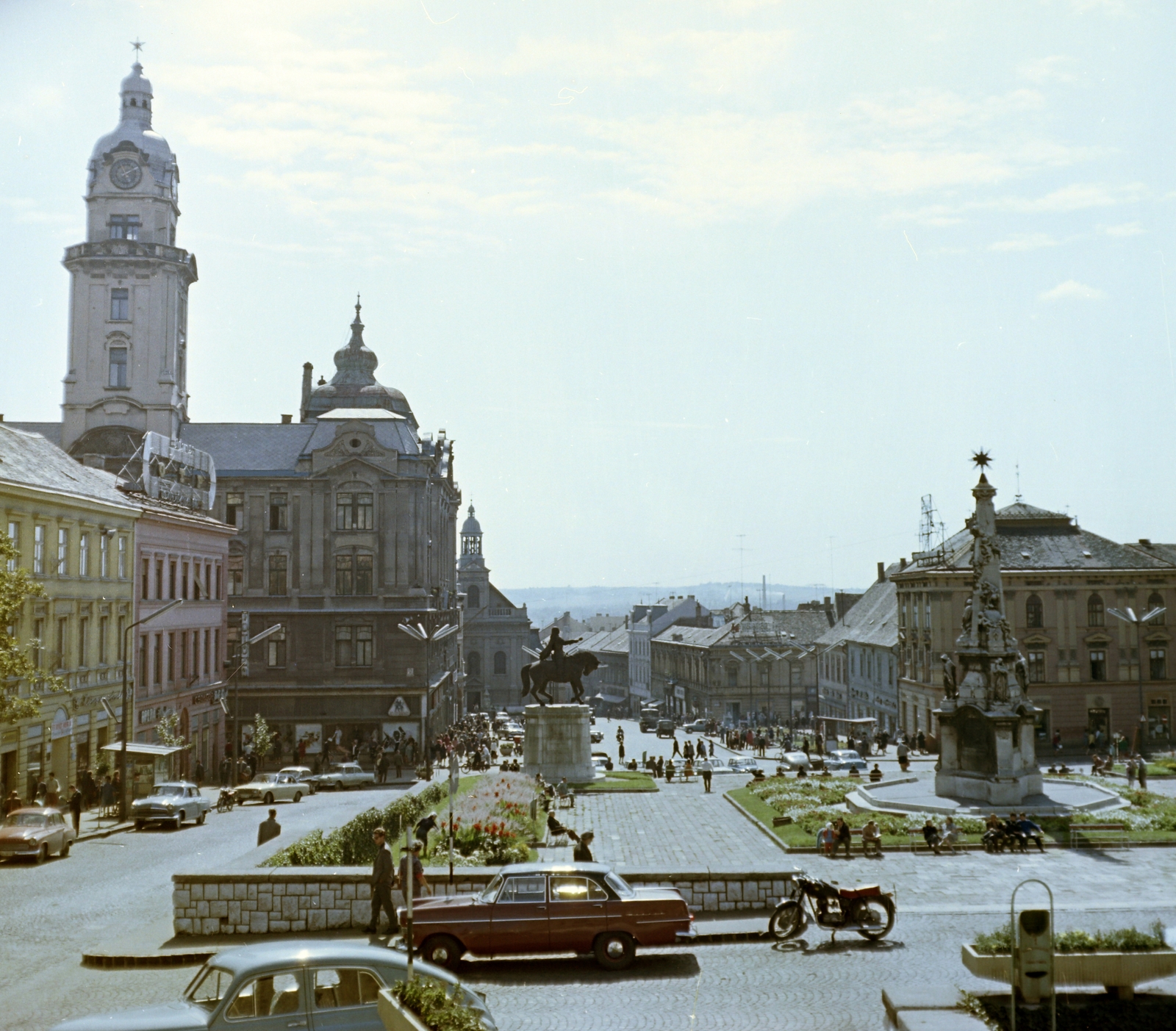 Hungary, Pécs, Széchenyi tér, kilátás a Dzsámi felől. Balra a Városháza tornyos épülete, középen Hunyadi János szobra, jobbra a Szentháromság-szobor., 1965, Faragó György, motorcycle, colorful, automobile, Opel-brand, horse sculpture, Holy Trinity Statue, car park, Fortepan #260979