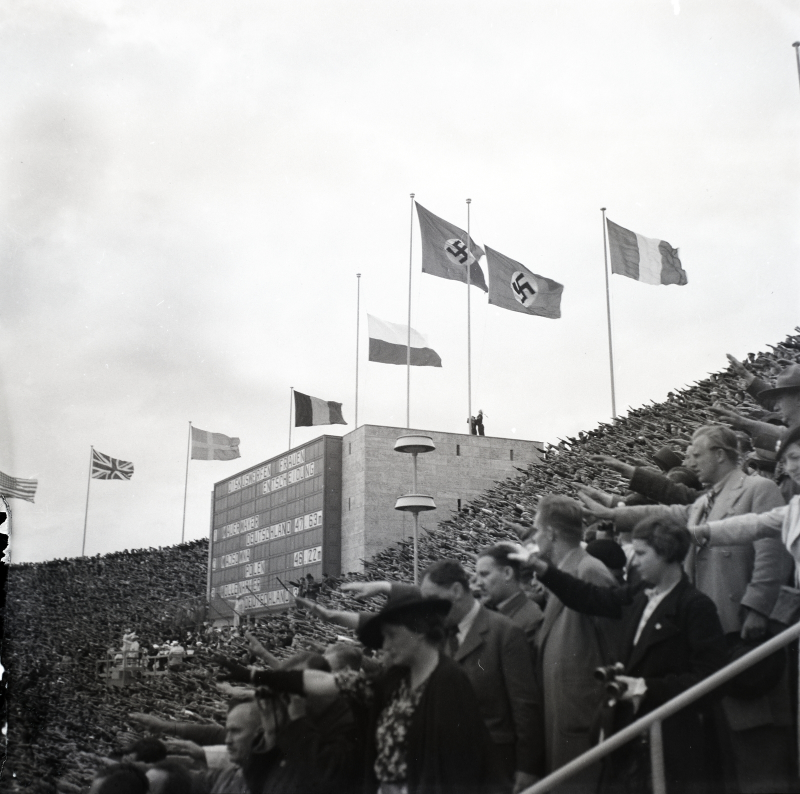 Germany, Berlin, Olimpiai Stadion, a XI. nyári olimpiai játékok női diszkoszvetésének eredményhirdetése alatt., 1936, Lőrincze Judit, swastica, Berlin Olympics, Olympics, posture, stadium, scoreboard, bunting, Fortepan #26125
