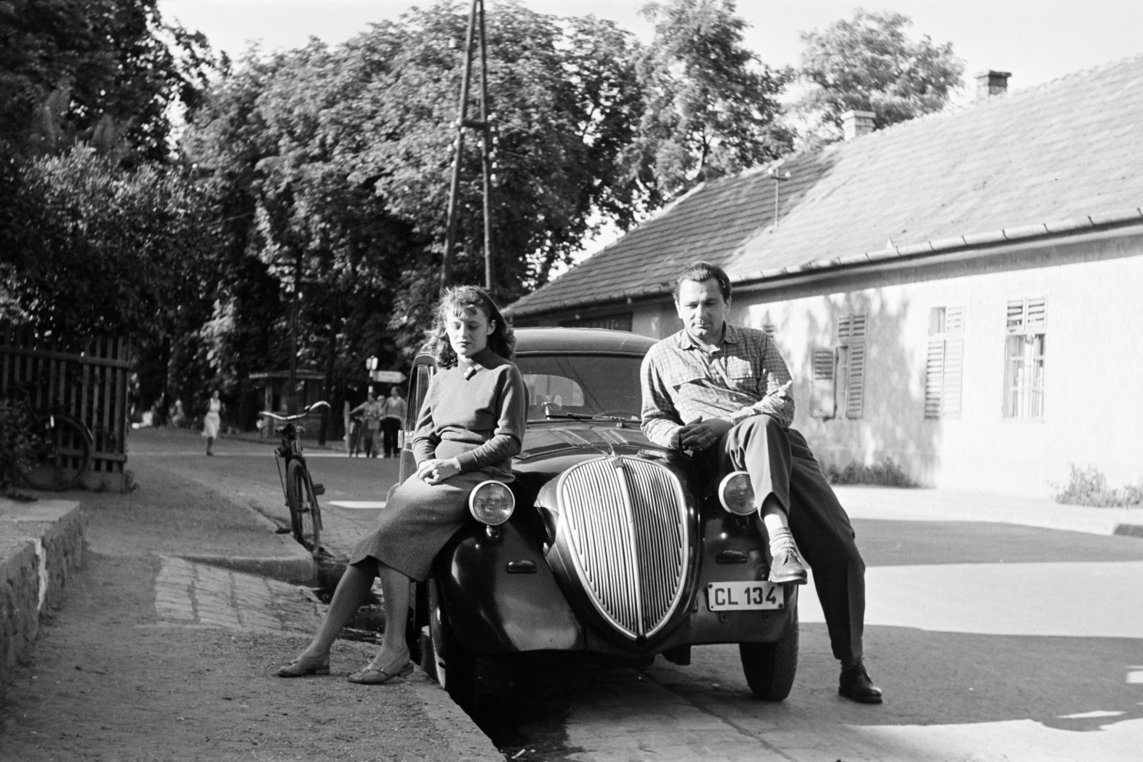 Hungary, Leányfalu, Móricz Zsigmond út (11-es főút), háttérben a Gyulai Pál utca kereszteződésénél az irányjelző tábla a hajóállomást mutatja., 1955, Faragó György, youth, sitting on a car, relaxation, bicycle, Fortepan #261511