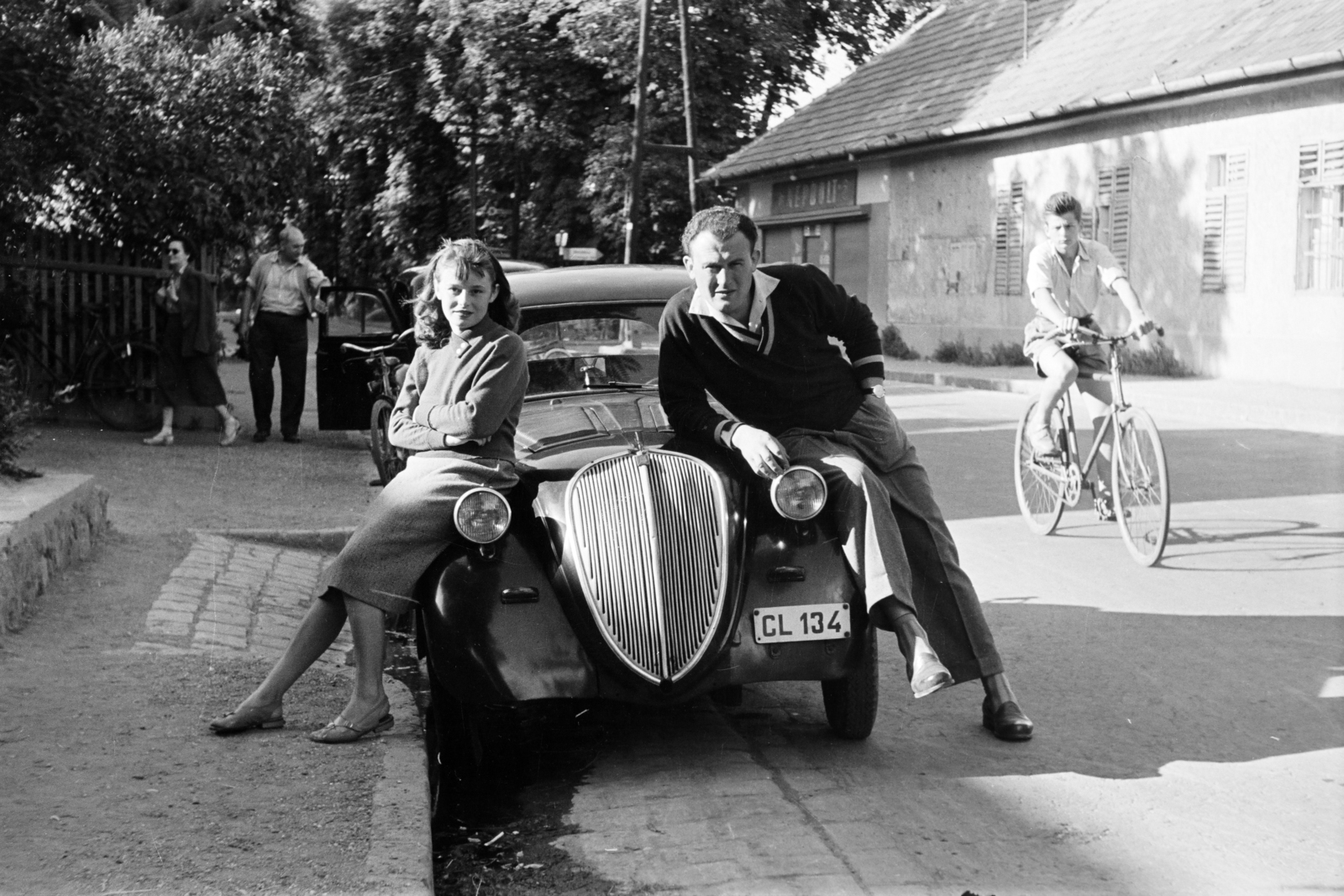 Hungary, Leányfalu, Móricz Zsigmond út (11-es főút), háttérben a Gyulai Pál utca kereszteződésénél az irányjelző tábla a hajóállomást mutatja., 1955, Faragó György, Best of, automobile, bicycle, youth, number plate, sitting on a car, Fortepan #261512