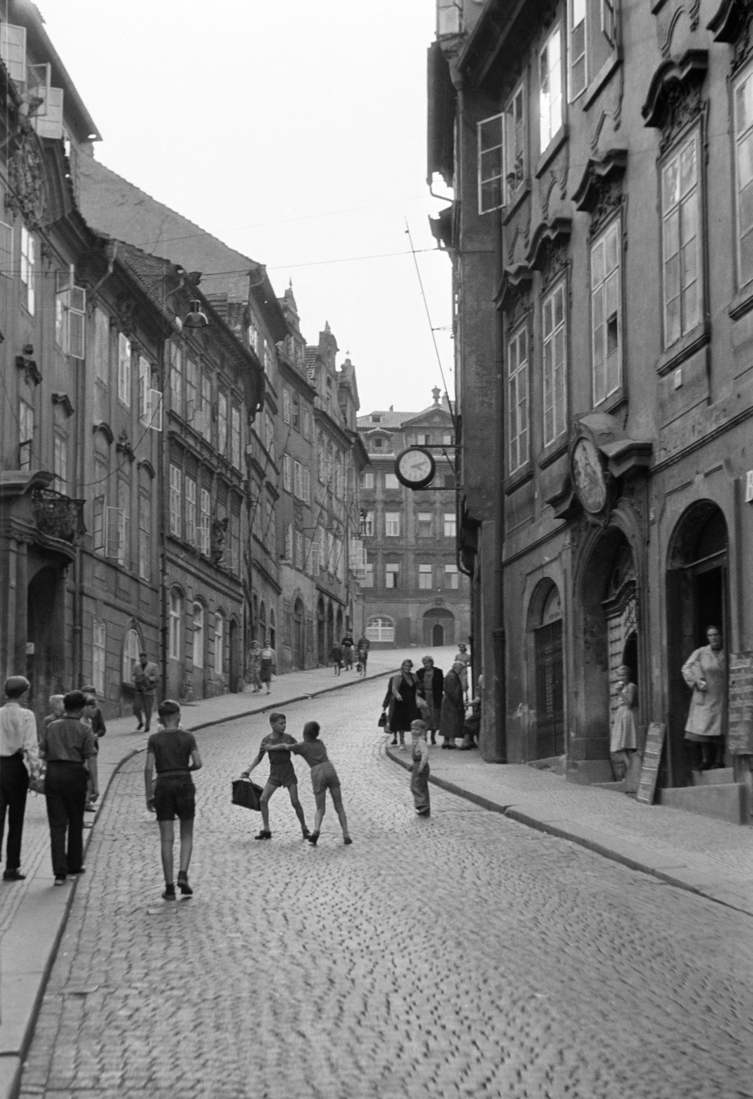 Czech Republik, Prague, Nerudova ulice az ulice Ke Hradu felé. Jobbra a 34. szám alatti az Arany Patkóhoz (U Zlaté podkovy) étterem és szálloda., 1956, Faragó György, street view, public clock, genre painting, Czechoslovakia, Fortepan #261631