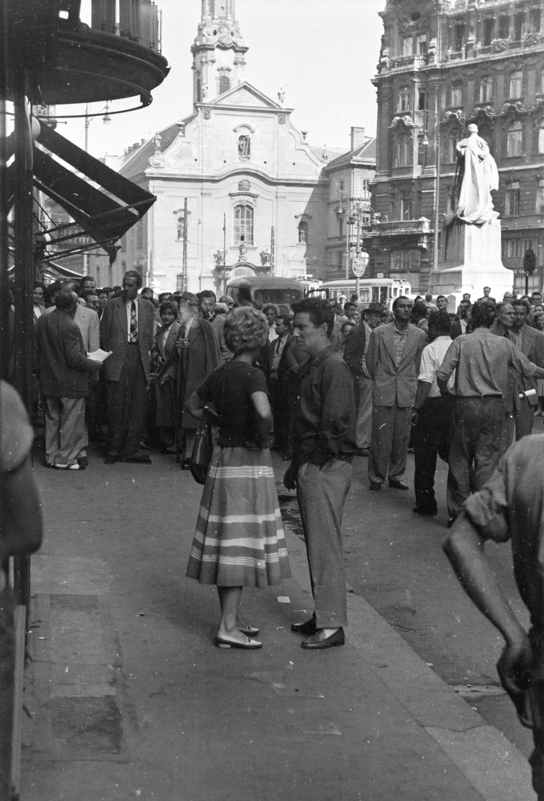 Hungary, Budapest V., Kígyó utca, a felvétel az Apostolok étterem előtt, a Csendes otthon című filmvígjáték forgatásán készült. Középpontban a film főszereplői Galambos Erzsi és Zenthe Ferenc színművészek. Jobbra a háttérben Pázmány Péter szobra (Radnai Béla, 1914.). Távolabb a Ferenciek tere (Felszabadulás tér) és a Belvárosi Ferences templom látható, 1957, Faragó György, actor, filming, celebrity, sculpture, church, Budapest, Fortepan #261830
