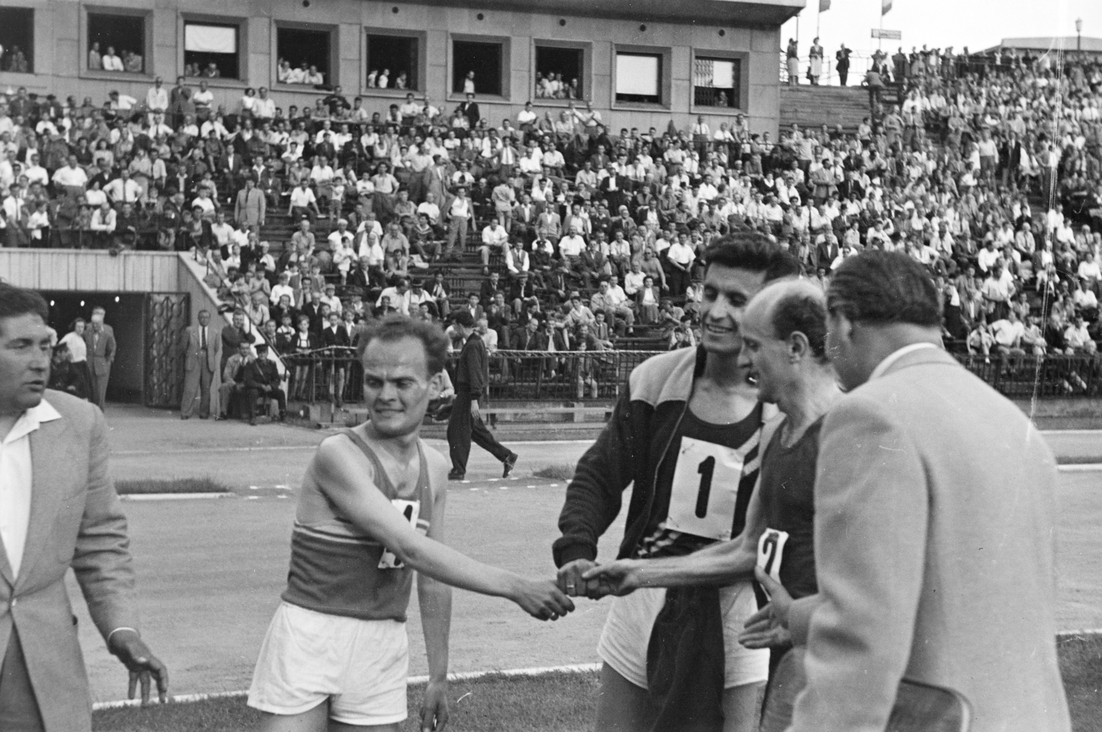 Magyarország, Népstadion, Budapest XIV., középen Kovács József, Veliša Mugoša (Jugoszlávia) és Szabó Miklós hosszútávfutók. A felvétel 1957. május 19-én készült., 1957, Faragó György, néző, rajtszám, nézőtér, kézfogás, futás, stadion, Budapest, Fortepan #261856