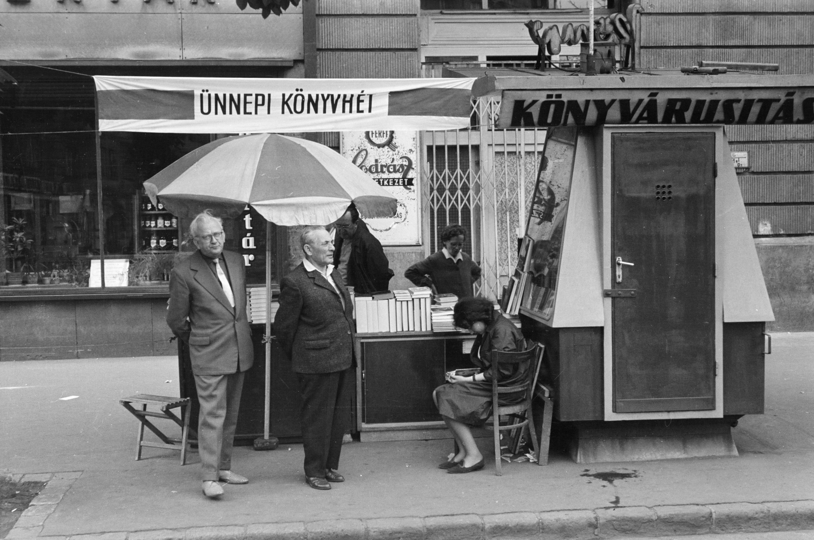 Hungary, Budapest XI., az Ünnepi könyvhét kiadványait árusító pavilon a Bartók Béla út 51. számú ház előtt. Bal szélen Kodolányi Gyula költő, műfordító, irodalomtörténész., 1967, Gyulai Gaál Krisztián, Budapest, reading, sunshades, poster, hairdresser, book fair, Fortepan #262233