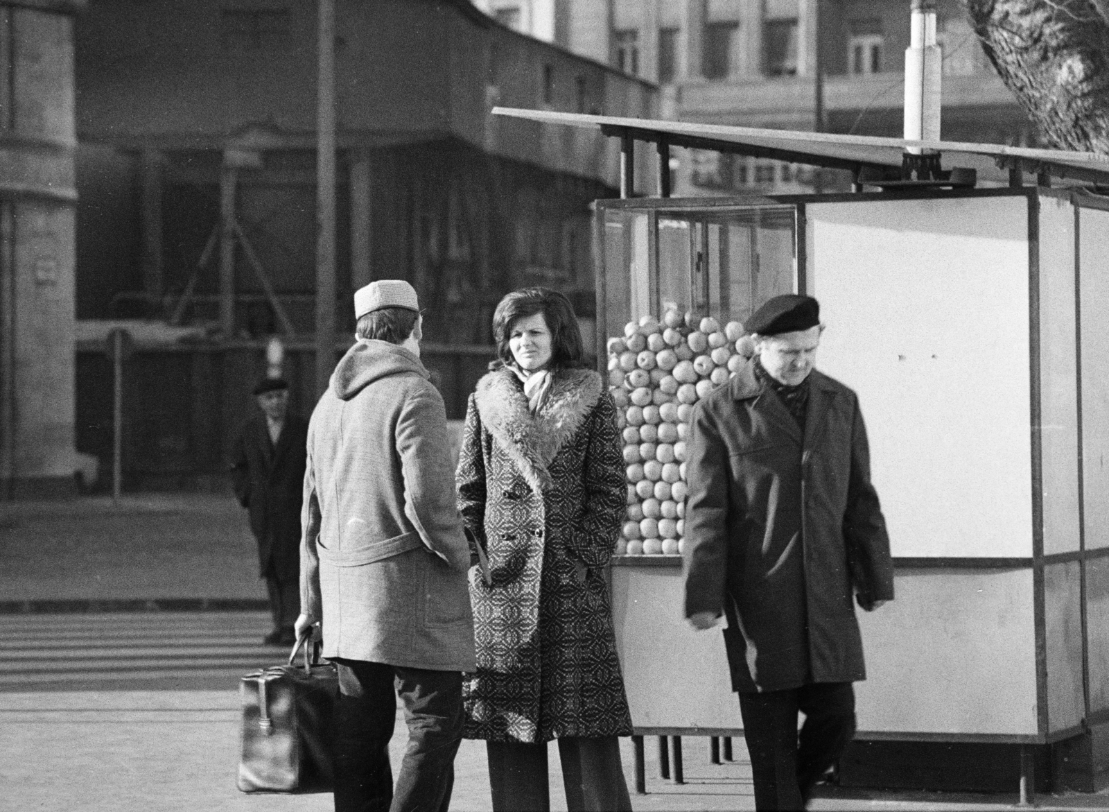 Magyarország, Budapest V., Erzsébet (Engels) tér, a Budapesti Rendőr-főkapitányság épülete előtt. Háttérben a Bécsi utca 10-es számú ház látható., 1972, Gyulai Gaál Krisztián, Budapest, beszélgetés, zsebredugott kéz, pavilon, életkép, télikabát, gyümölcsárus, Fortepan #262673