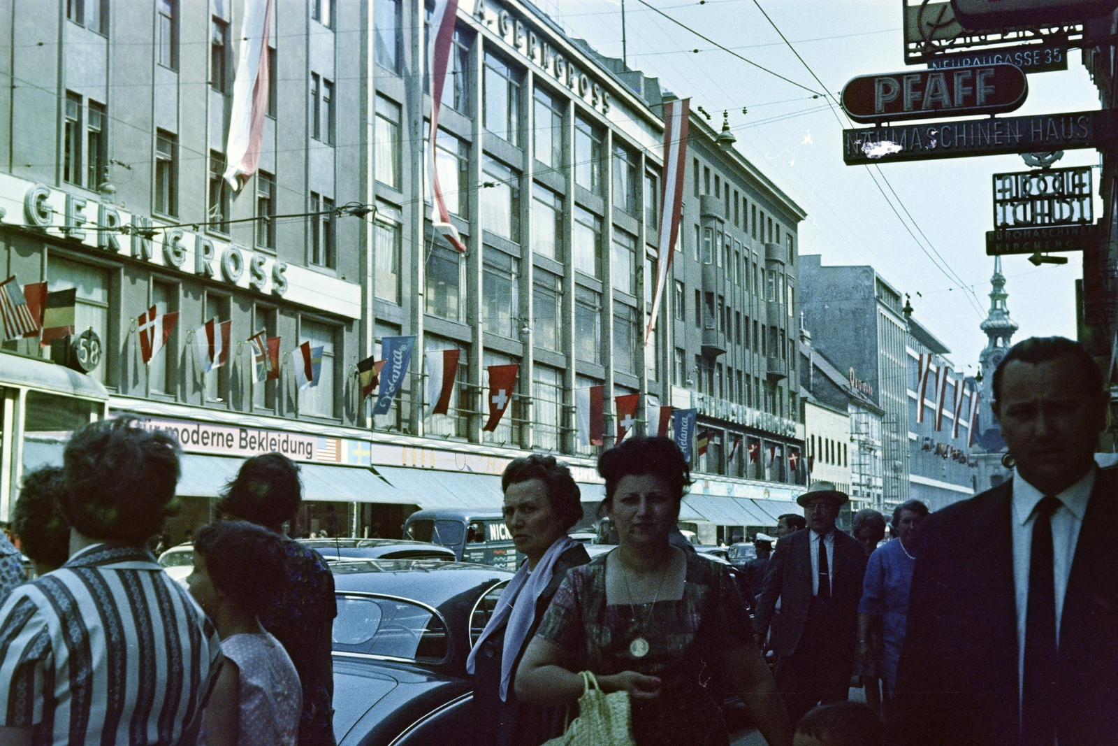 Austria, Vienna, Mariahilfer Strasse a Kirchengasse felől a Stiftgasse felé nézve, balra a Gerngross Áruház épülettömbje, jobbra a háttérben a Stiftskirche zum Heiligen Kreuz tornya látható., 1962, Szűcs Attila, Fortepan #263176