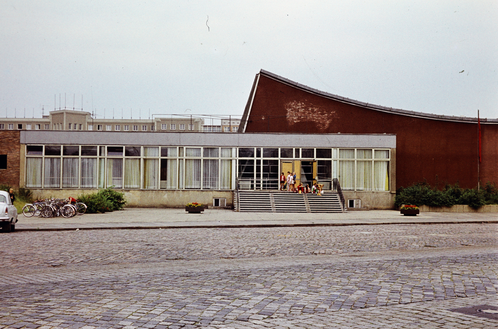 Germany, Dresden, Freiberger Platz, Schwimm- und Sprunghalle (fedett uszoda valamint mű- és toronyugrócsarnok), háttérben a Német Szocialista Egységpárt (NSZEP) / Sozialistische Einheitspartei Deutschlands (SED) körzeti pártiskolájának az épülete (később Boulevardtheater Dresden)., 1967, Fortepan/Album074, bicycle holder, colorful, Fortepan #263303