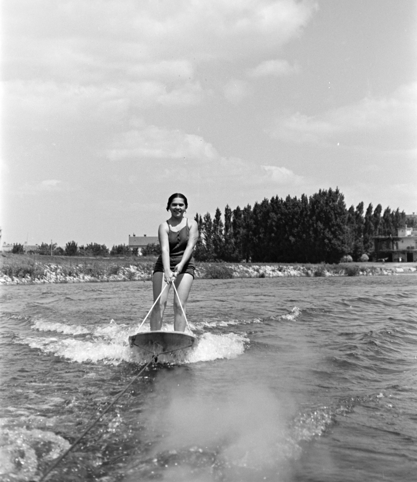 Hungary, Győr, "vízideszkázó" a Mosoni-Dunán, háttérben a Győri Torna a Győri Torna és Evezős Egylet (később Rába ETO, ma Győri Vízügy-Spartacus Evezős Klub) csónakháza., 1938, Nagy István, portrait, smile, summer, water, surf, Fortepan #264218