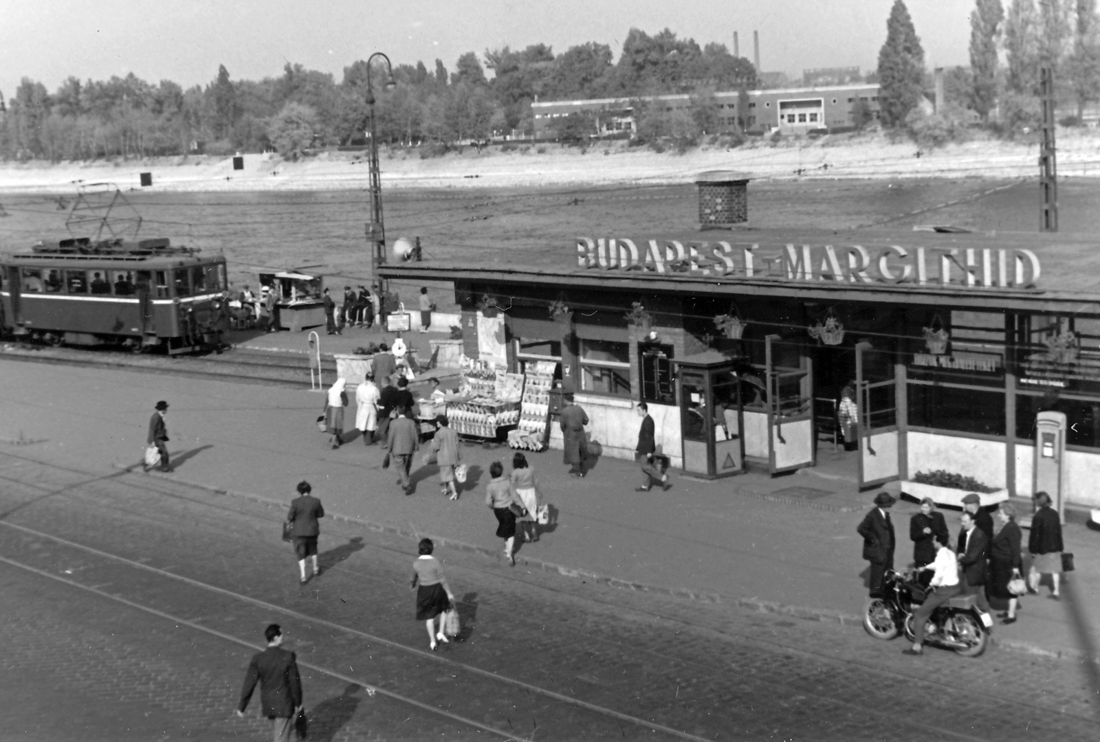 Hungary, Budapest II., Margit híd budai hídfő, HÉV végállomás. Háttérben a Margitszigeti Úttörő sporttelep / Úttörő stadion (később Margitszigeti Atlétikai Centrum)., 1954, Jurányi Attila, motorcycle, genre painting, buffet, phone booth, waiting room, newsstand, speaker, commuter train, Budapest, scale, Fortepan #26448