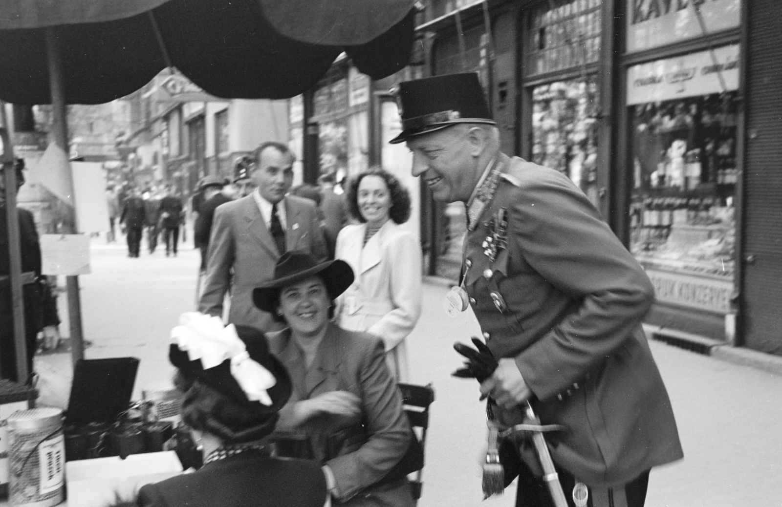 Magyarország, Budapest V., Ferenciek tere, háttérben középen a Curia utca torkolata. Béldy Alajos altábornagy egy adománygyűjtő asztalnál., 1943, Horváth József, magyar katona, kirakat, kardbojt, kard, vöröskereszt, adománygyűjtés, kitüntetés, Budapest, Fortepan #265041