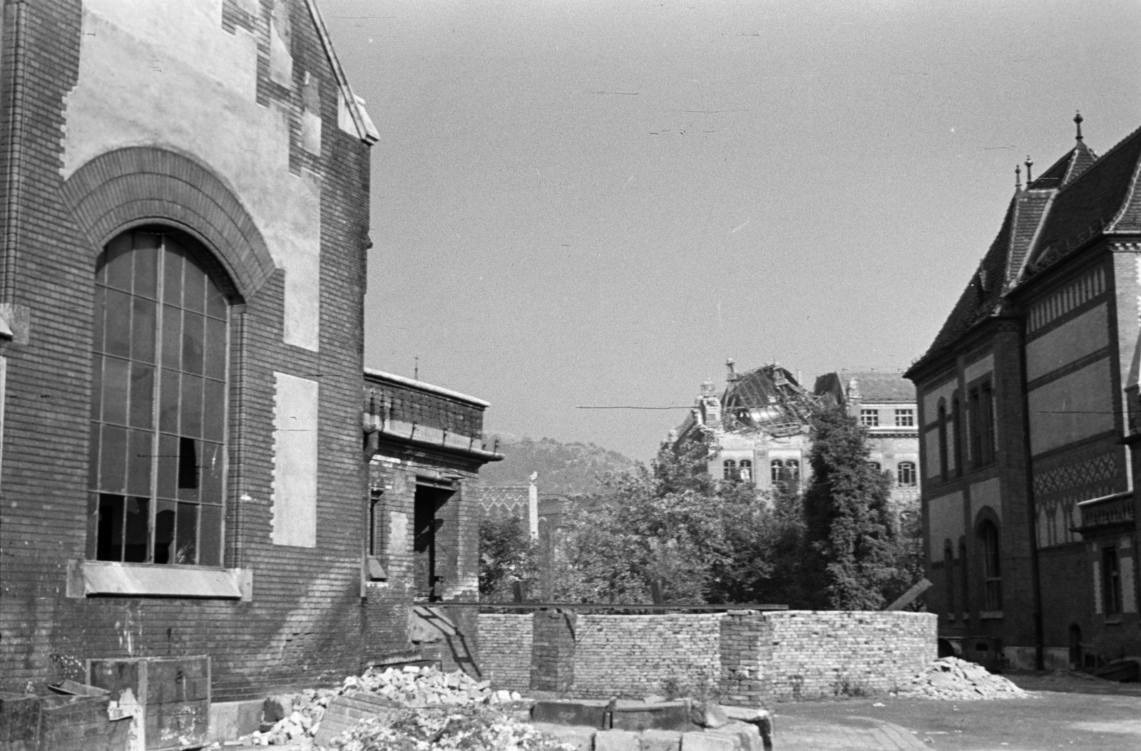 Magyarország, Budapest XI., a Magyar királyi József nádor Műszaki és Gazdaságtudományi Egyetem (később Budapesti Műszaki és Gazdaságtudományi Egyetem) a Bertalan Lajos utca felől nézve. Balra az Hő, középen a K, jobbra az MT épület, háttérben a Gellért-hegy., 1944, Horváth József, Budapest, épületkár, Fortepan #265117