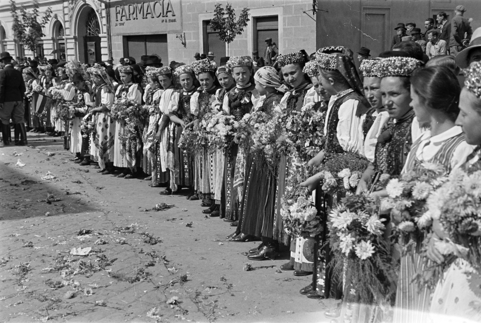 Romania,Transylvania, Huedin, Kossuth Lajos utca (Fő utca, strada Horea), bal szélen a Takarékpénztár épülete. Népviseletbe öltözött lányok sorfala. A felvétel a magyar csapatok bevonulása idején, 1940. szeptember 11-én készült., 1940, Horváth József, folk costume, pharmacy, conscription, bouquet, Fortepan #265459
