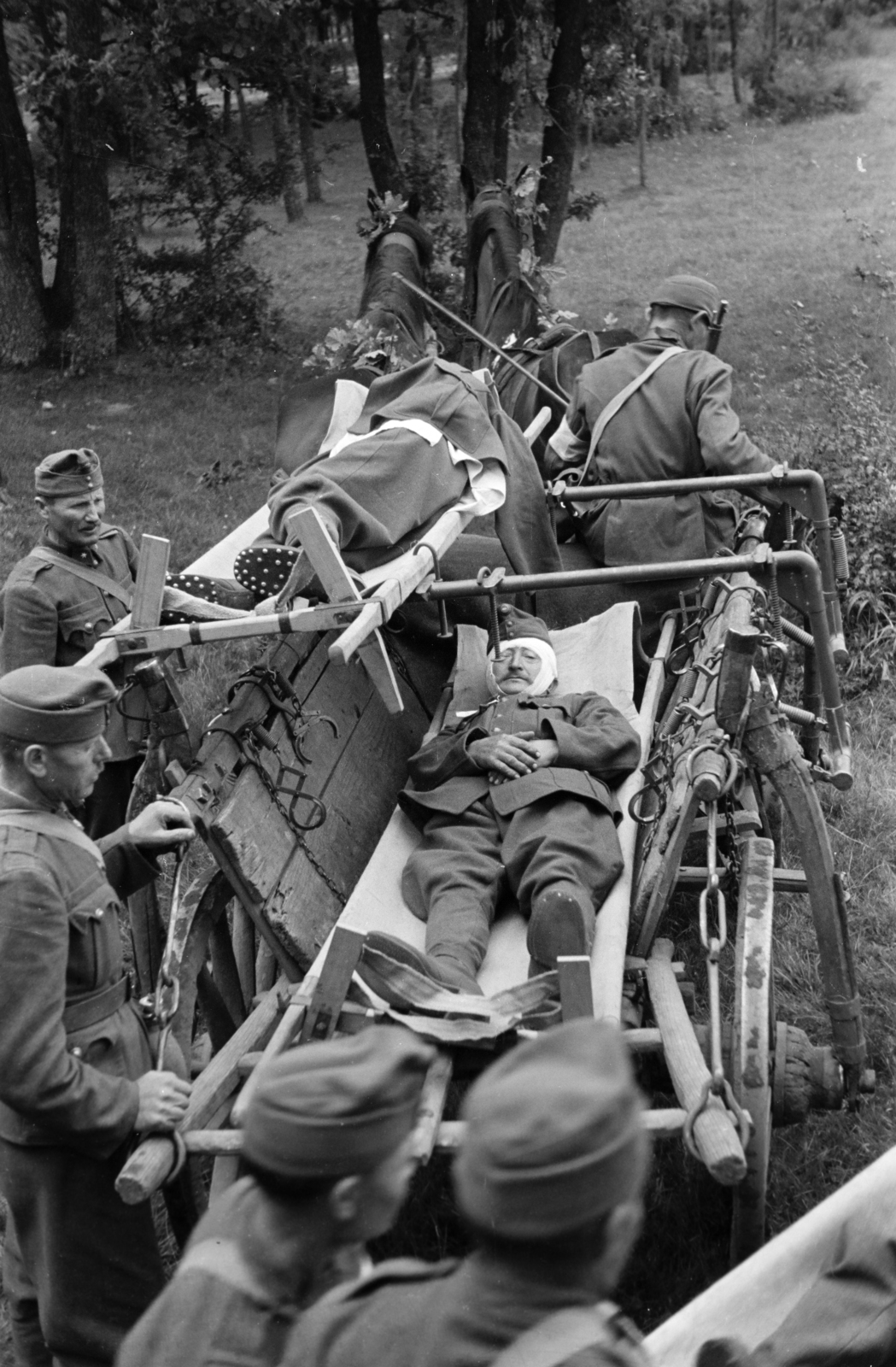 Hungary, sebesültszállítást gyakorló katonák. A dr. Frank orvos tábornok tervezte, hordágyfüggesztővel felszerelt, országos jármű / katonai célokra kifejlesztett, alkatrészeiben szabványosított faanyagú, ló vontatta szekerek. Balra lombokkal álcázott mentőautók láthatók., 1940, Horváth József, chariot, wounded, barrow, soldier, horse, Fortepan #265511
