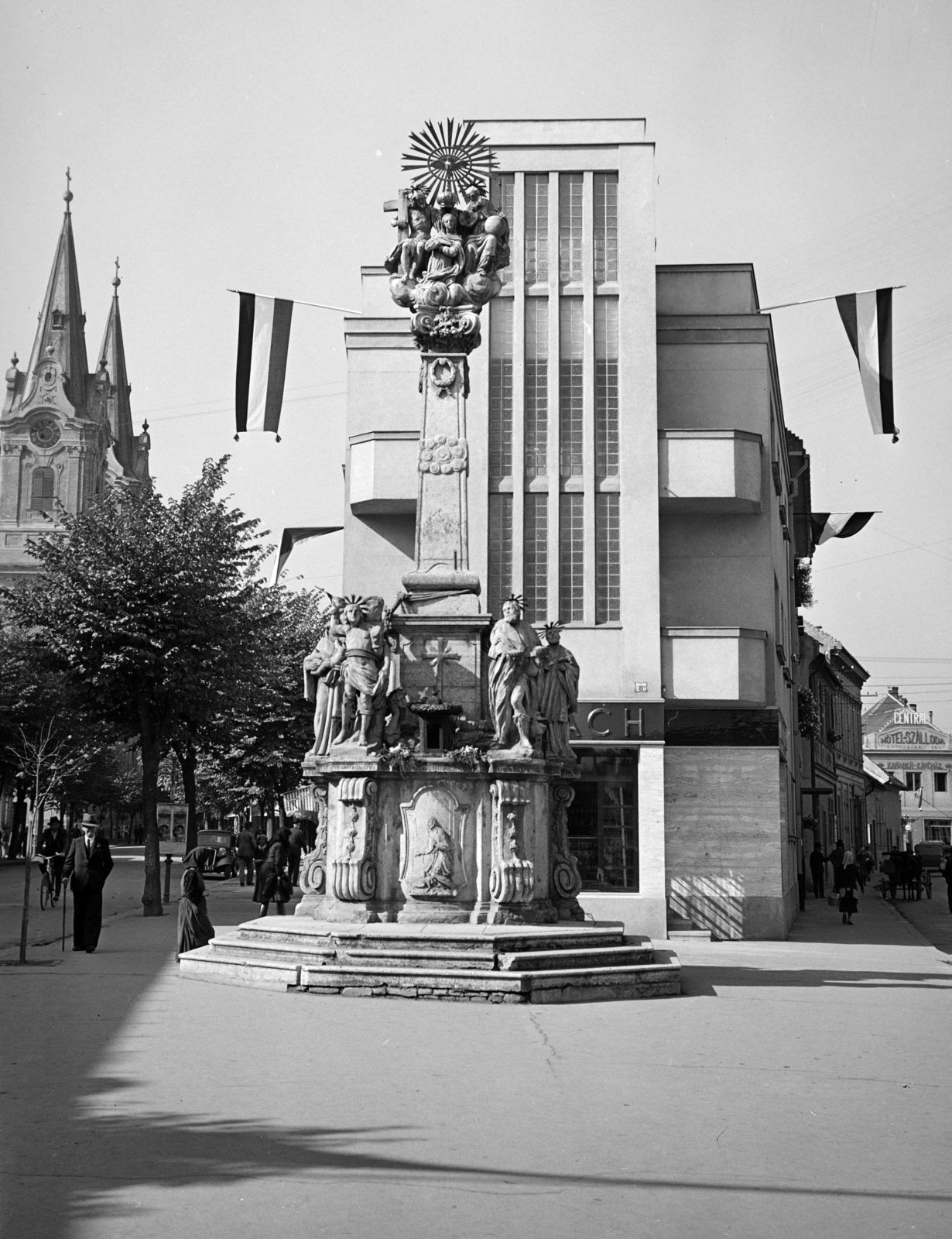 Szlovákia, Komárom, Szentháromság-szobor a Klapka György téren (námestie generála Klapku). Balra a Nádor utca (Palatinova ulica) és a Szent András-templom. Jobbra a Megye utca (Zupná ulica)., 1938, Horváth József, Best of, zászló, szentháromság szobor, Fortepan #265912