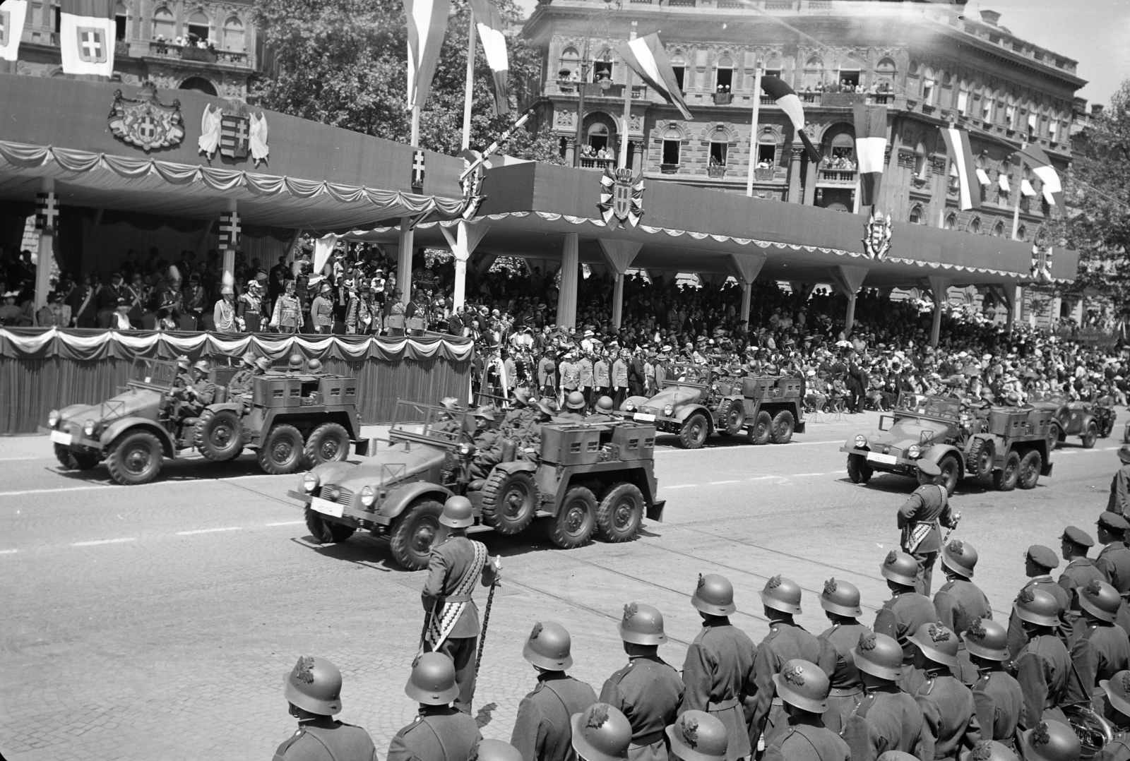 Hungary, Budapest VI., Kodály körönd (Körönd), III. Viktor Emánuel olasz király tiszteletére rendezett katonai díszszemle 1937. május 20-án. A tüzérség felvonulása a dísztribün előtt., 1937, Horváth József, grandstand, helmet, crest, parade, artillery tractor, flag, drum major, Budapest, Fortepan #266075