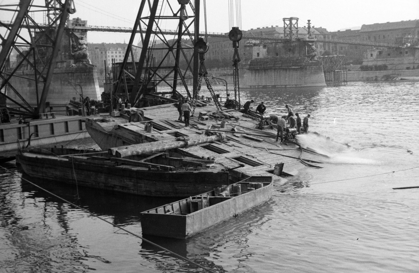 Magyarország, Margitsziget, Budapest II., a lerombolt Margit híd újjáépítésén dolgozó Ady Endre és József Attila úszódaru, a felvétel a Margitsziget partjáról készült. Háttérben a híd pillérein épült, fajármokra szerelt, közművezetékeket is hordozó kábelhíd, jobbra a budai hídfő látható., 1947, Vízkelety László, Budapest, hajódaru, Fortepan #266153