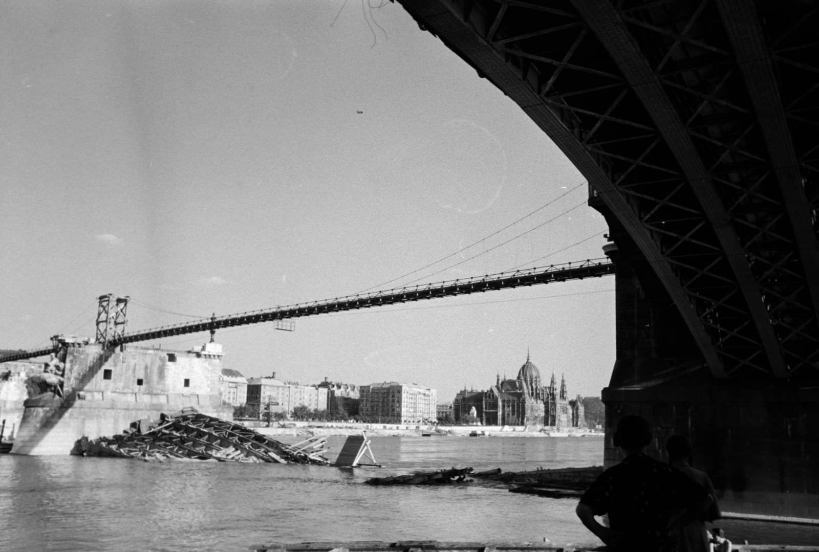 Hungary, Margit Islands, Budapest, a felvétel a Margitsziget partjáról a lerombolt Margit híd roncsainak kiemelésekor készült. Fent a híd pillérein épült, fajármokra szerelt, közművezetékeket is hordozó kábelhíd és távolabb a Parlament látható., 1947, Vízkelety László, wrecked bridge, Fortepan #266259