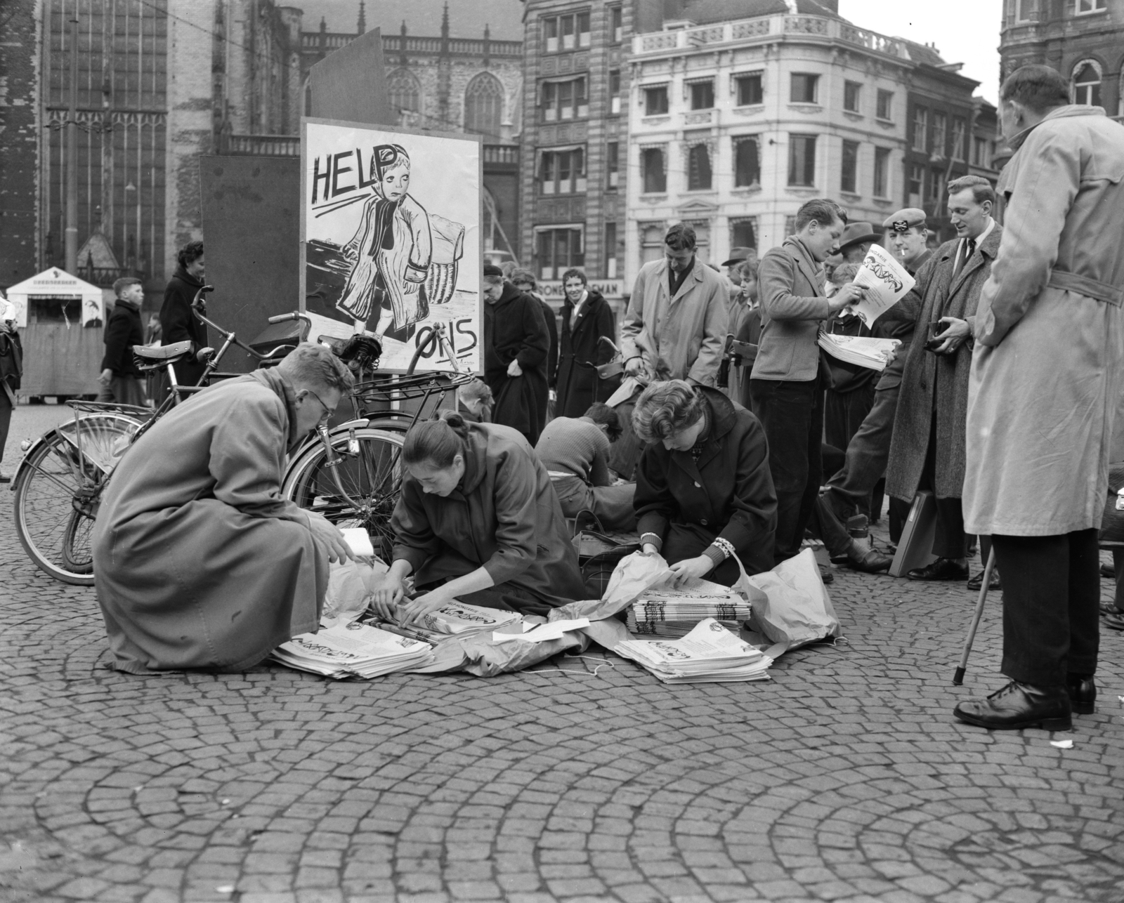 Netherlands, Amsterdam, Dam tér, a Magyarország megsegítésére indított, 1956-os adománygyűjtésekor, egyetemisták újságot árulnak., 1956, Nationaal Archief, poster, youth, newspaper, solidarity, badge, bicycle, Fortepan #267179