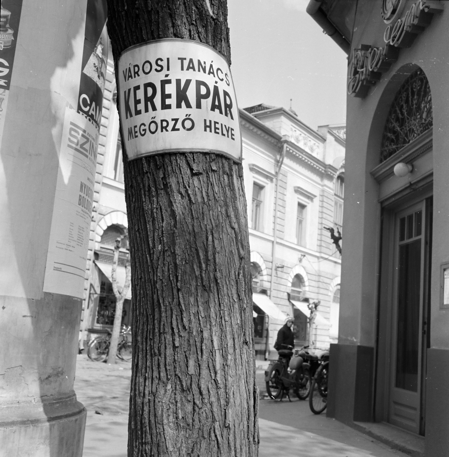 Hungary, Cegléd, Kossuth tér, a felvétel a Földművesszövetkezeti (később Alföldi) Étterem előtt készült, háttérben balra a Szövetkezeti Aruház látható., 1971, Gárdos Katalin, bicycle, bicycle holder, enamel sign, Fortepan #268137