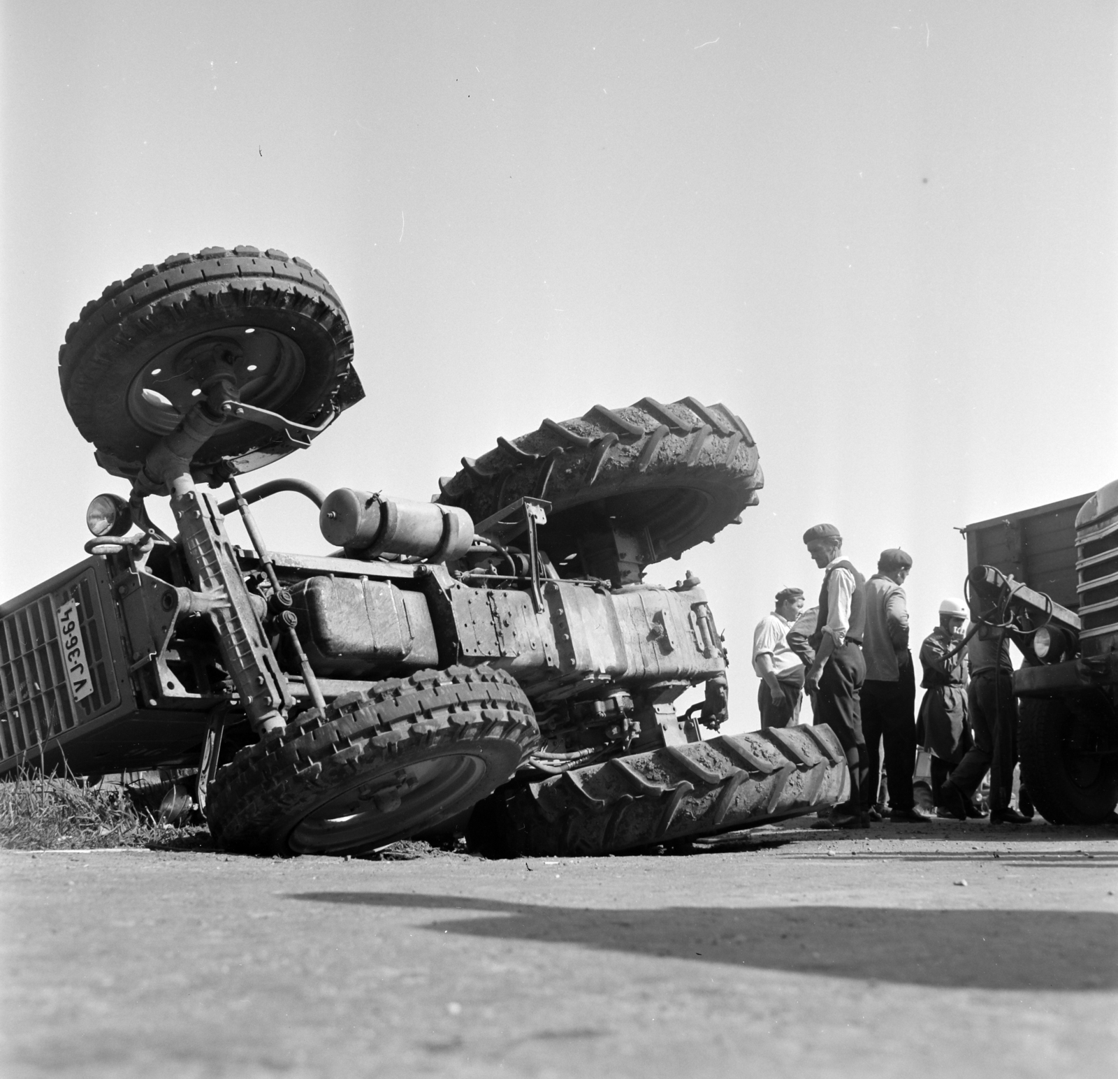 Hungary, Pilis, egy teherautó szabálytalan előzése miatt az előtte kanyarodó, két pótkocsit vontató traktor a karambol következtében az útpadkán felborult., 1971, Gárdos Katalin, accident, tractor, number plate, Fortepan #268222