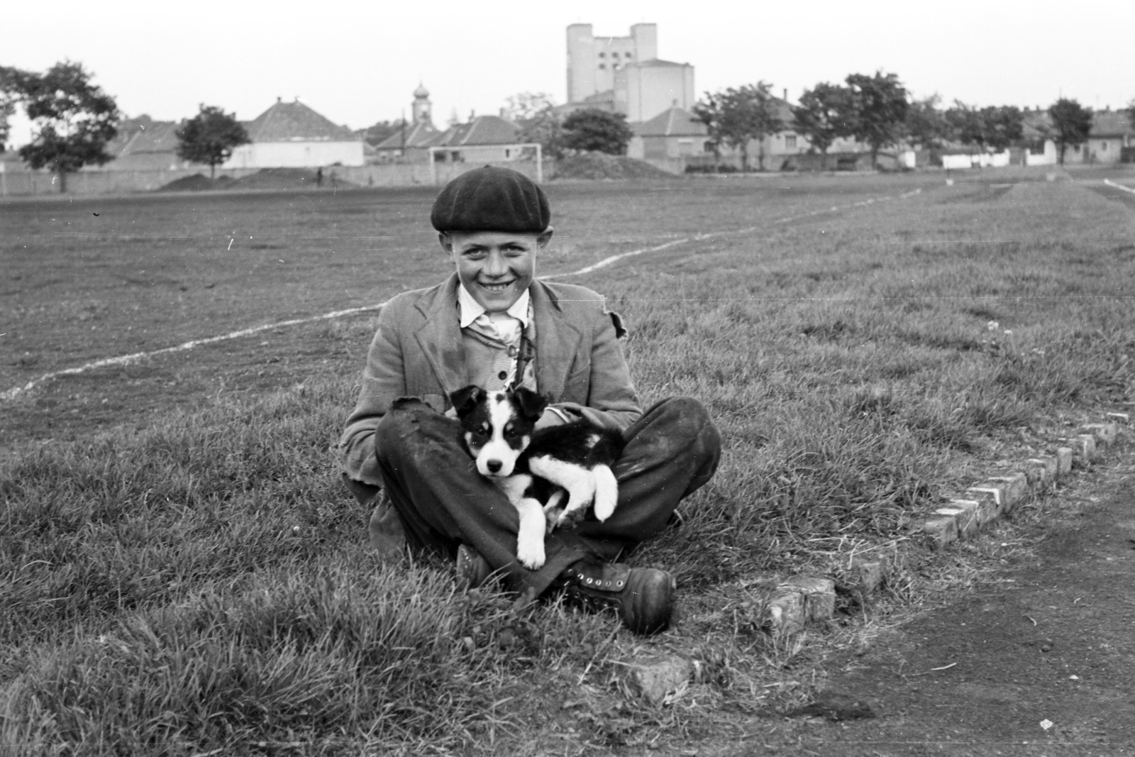 Hungary, Csorna, sporttelep, háttérben a Nagyboldogasszony templom tornya, jobbra a Jézus Szíve-templom., 1961, Lipovits Károly, Best of, beret, puppy, dog, Fortepan #271763