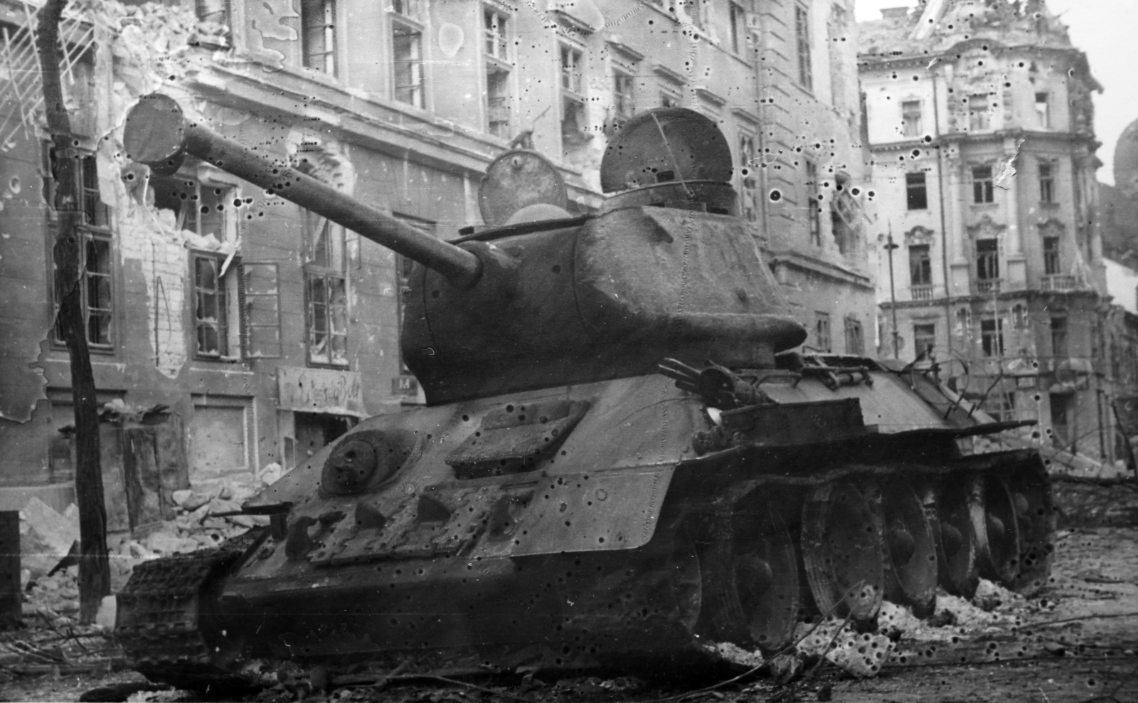 Hungary, Budapest IX., kilőtt szovjet T-34/85 harckocsi az Üllői úton, háttérben a Kilián laktanya és jobbra a Ferenc körút 46. számú romos épület., 1956, Fortepan/Album079, wreck, tank, revolution, peaked cap, untitled, combat vehicle, Budapest, Fortepan #272238