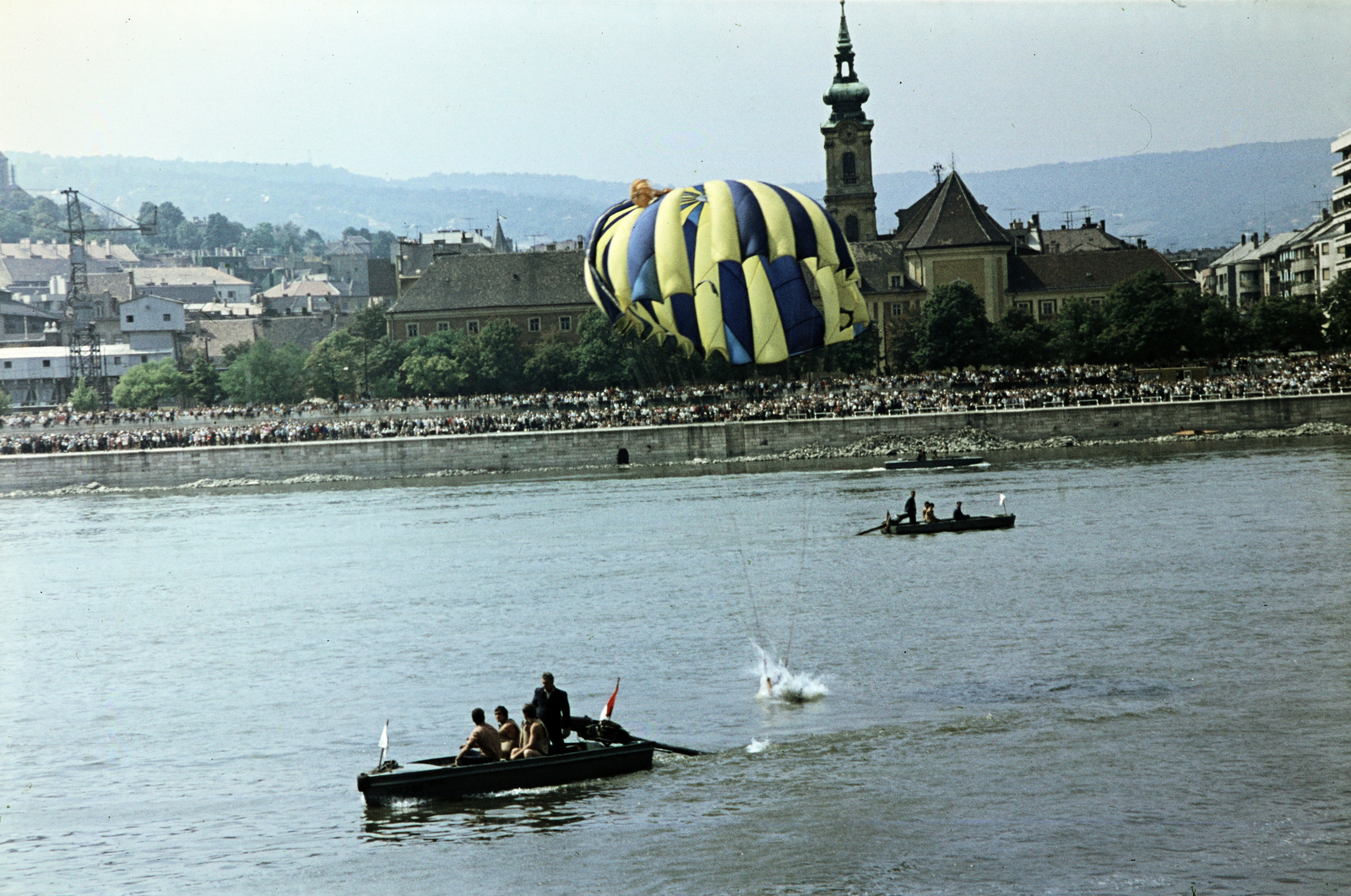 Magyarország, Budapest I.,Budapest II., augusztus 20-i vízi- és légiparádé, szemben a Bem rakpart. Az ejtőernyő takarásában a Szent Ferenc sebei templom és az egykori ferences kolostor., 1970, Kristek Pál, ejtőernyő, ejtőernyős, rohamcsónak, csónakmotor, Budapest, színes, Fortepan #274882