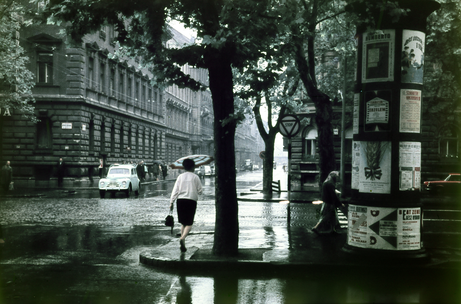 Magyarország, Budapest VI., Andrássy út (Népköztársaság útja) az Izabella utca kereszteződésnél, szemben a Podmaniczky (Rudas László) utca felé vezető szakasz., 1967, Kristek Pál, plakát, hirdetőoszlop, esernyő, eső, Budapest, Fortepan #274972