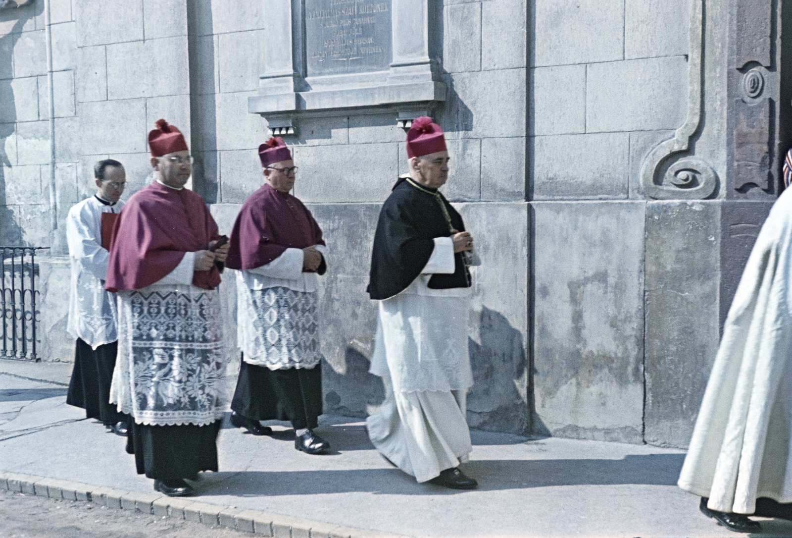 Hungary, Veszprém, Vár (Tolbuhin) utca, a felvétel a Szent István ferences templom előtt készült. A templom kapuja mellett, a falon Ányos Pál pálos szerzetes, tanár, a magyar szentimentalizmus költészetének alakjának emléktáblája. Elől Badalik Bertalan veszprémi püspök halad a papszentelés helyszínére, a Szent Mihály-székesegyház felé., 1956, Hámori Gyula, procession, cap, priest, memorial plaque, colorful, Fortepan #276210
