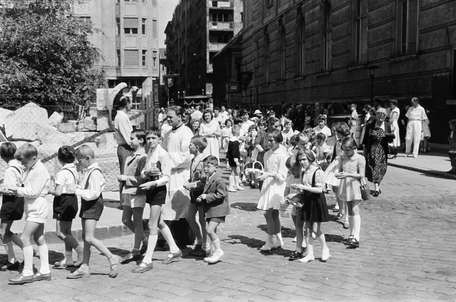 Magyarország, Budapest V., Március 15. tér, úrnapi körmenet résztvevői az ELTE Bölcsészkar (egykor és ma Piarista Gimnázium és Rendház) épülete előtt. Háttérben balra a Galamb utca torkolatánál álló épület látható., 1960, Hámori Gyula, Budapest, gyerekek, Fortepan #276494