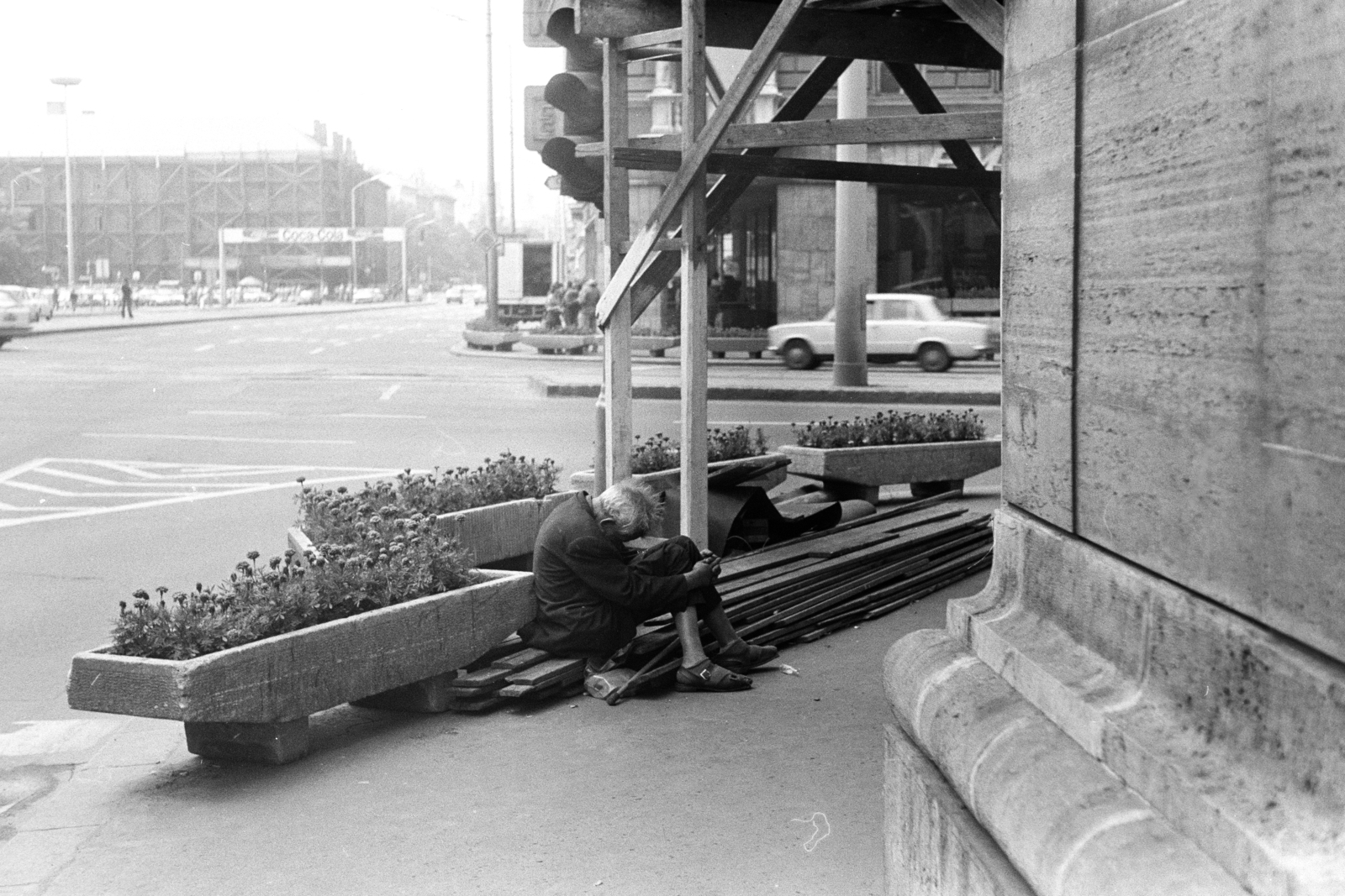 Hungary, Budapest VII.,Budapest VIII., Rákóczi út - Erzsébet (Lenin) körút sarok a Csemege Áruház / éjjel-nappal közért előtt. Háttérben balra a Blaha Lujza tér és a felállványozott Rókus kórház., 1981, Obetkó Miklós, scaffolding, beggar, Budapest, Fortepan #277366