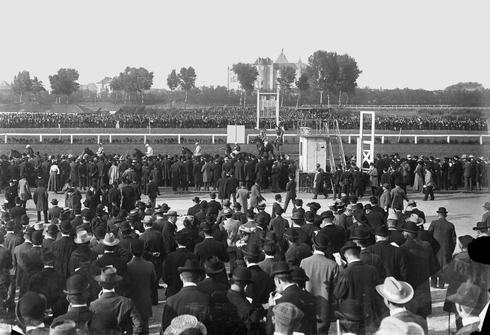 Magyarország, Budapest XIV., "városligeti" Lóversenytér a későbbi Népstadion helyén, nagyverseny előtti parádé. Háttérben a Magyar Állami Földtani Intézet látszik., 1903, Deutsche Fotothek / Brück und Sohn, közönség, lóverseny, zsoké, háttal, Budapest, Fortepan #277675